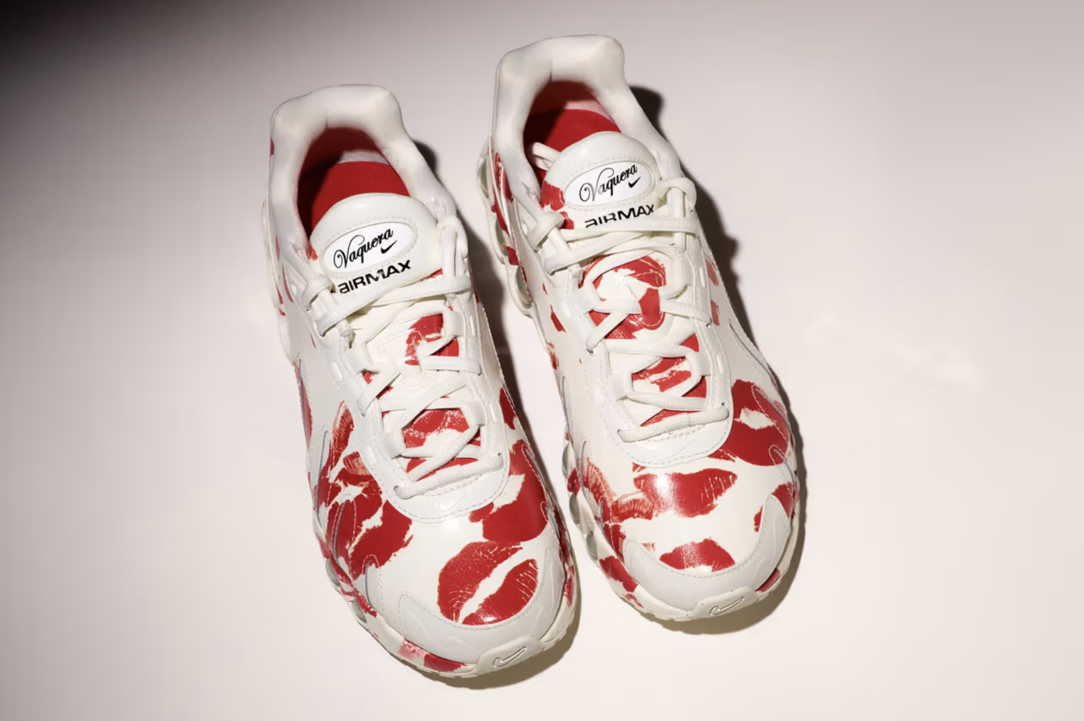 White sneakers with red lipstick print design and labels saying 'Vaquero' and 'Air Max' on a plain white background.