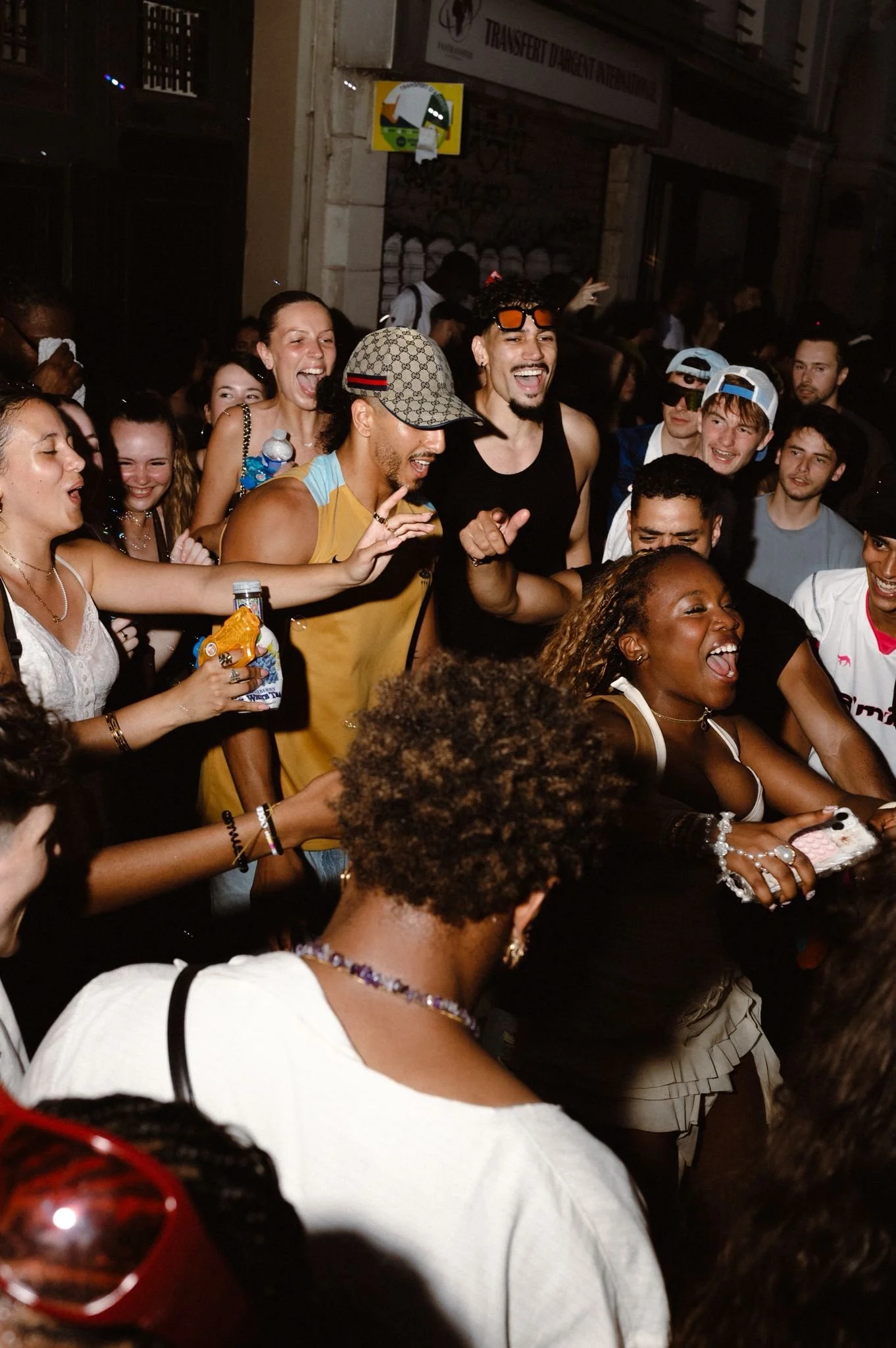 A diverse group of people smiling and dancing at a lively party or nightclub, enjoying the moment.