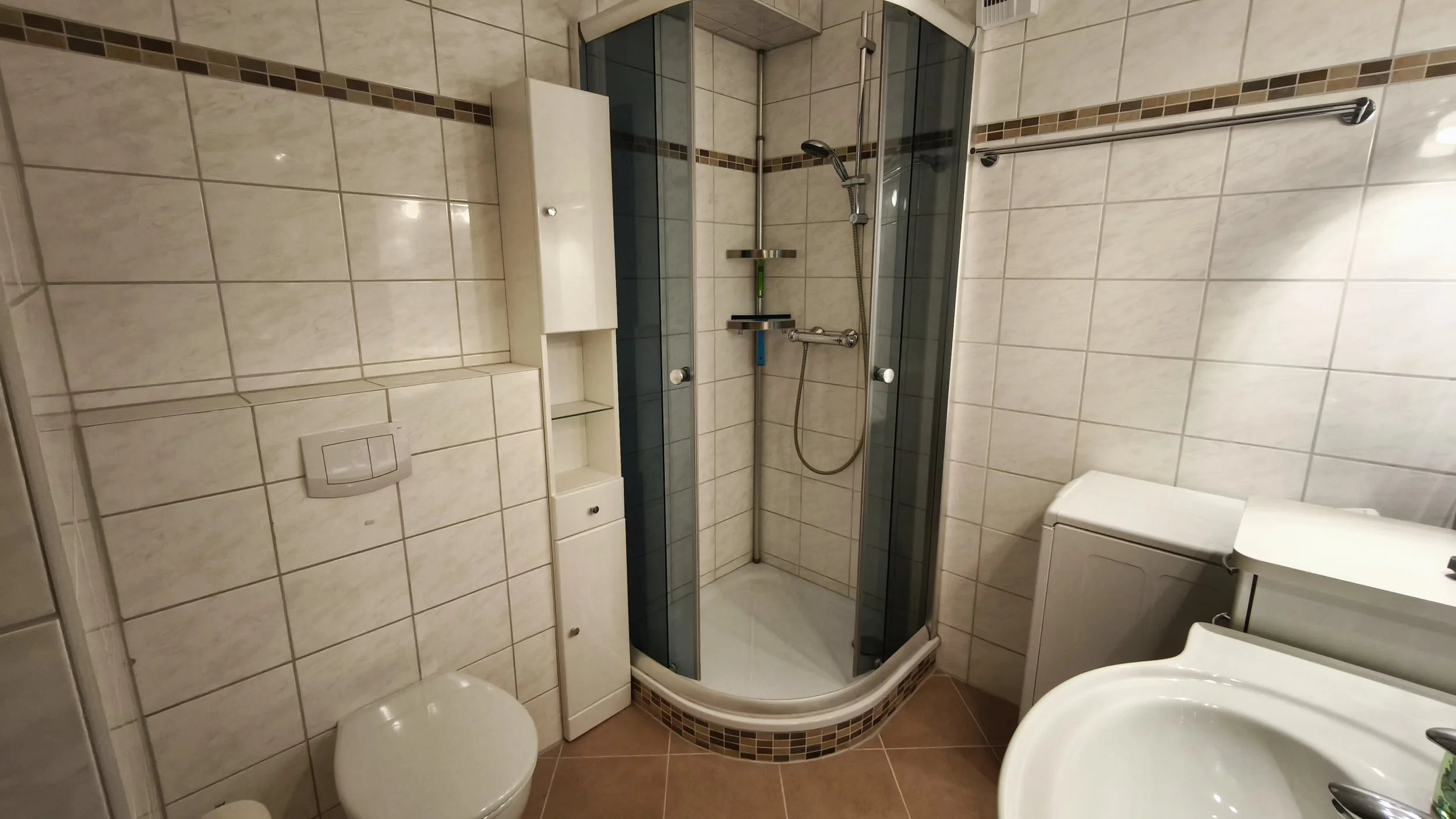 Komfortable Eckdusche und kleine Waschmaschine