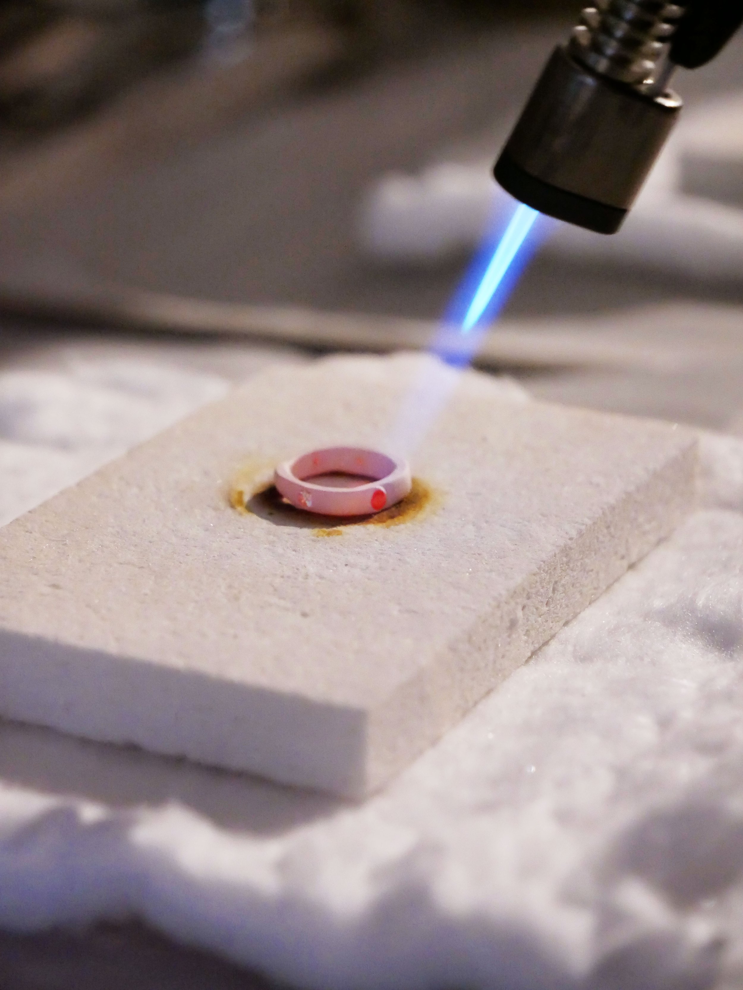 Un laser bleu est dirigé vers un anneau rose posé sur une surface en papier ou en tissu.