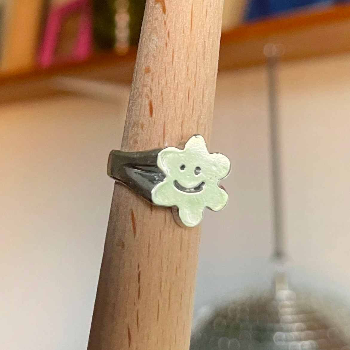 Bague noire avec un grain de lotus souriant en relief, portée sur un doigt