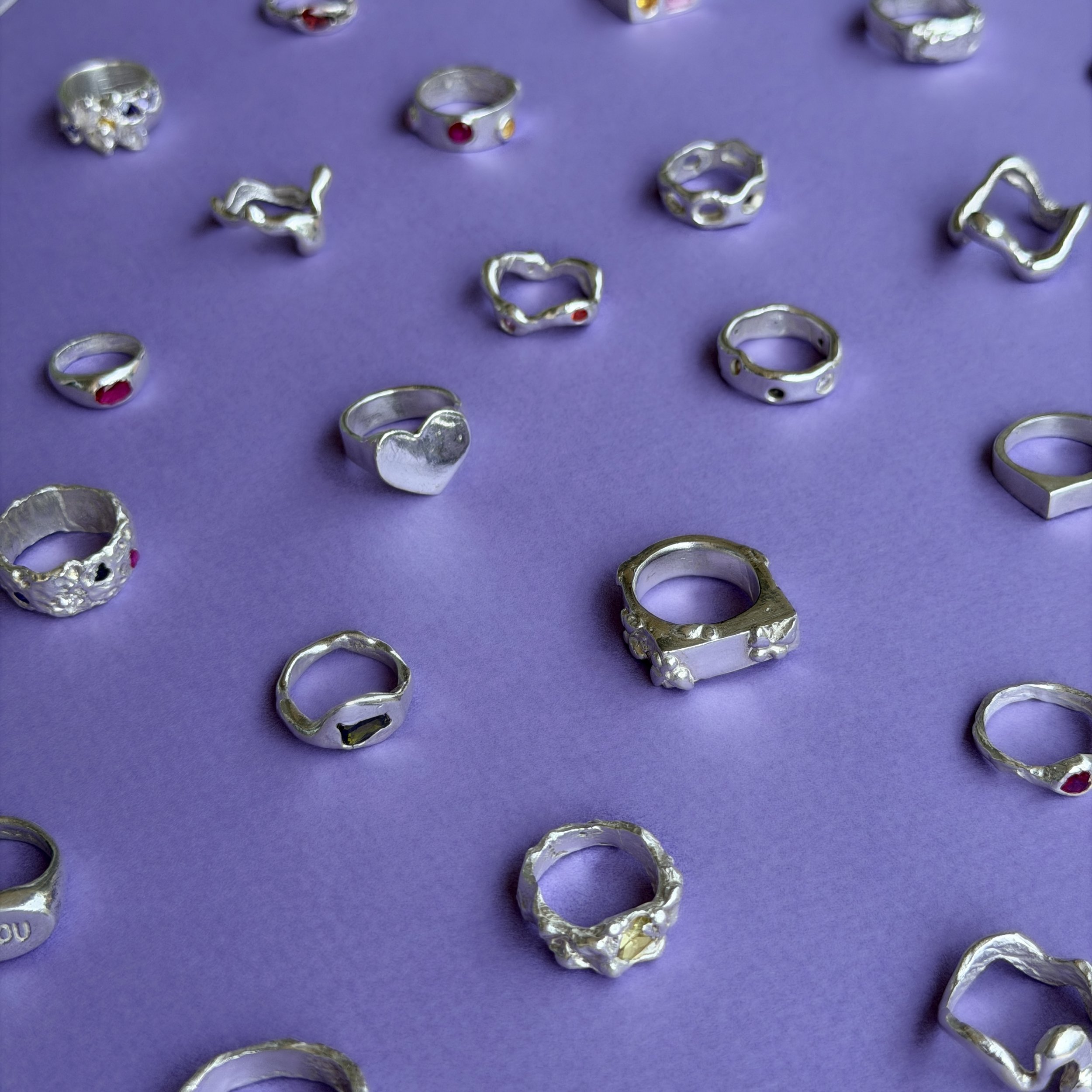 Collection de bagues en argent avec différentes formes, posés sur un tissu orange