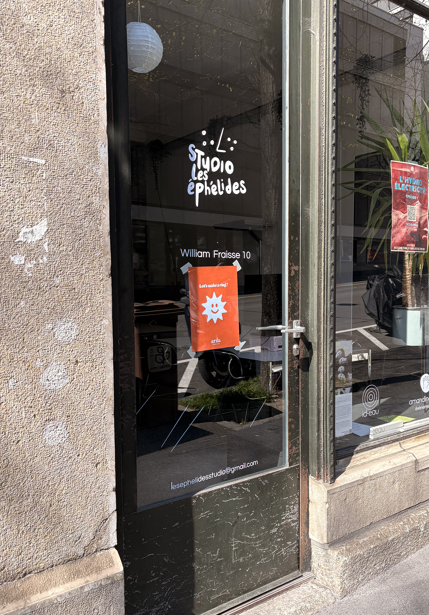 Vitrine d'un studio de création nommé 'Studio Les Éphélides' avec une affiche rouge et un logo blanc, située au 10 William Fraisse.