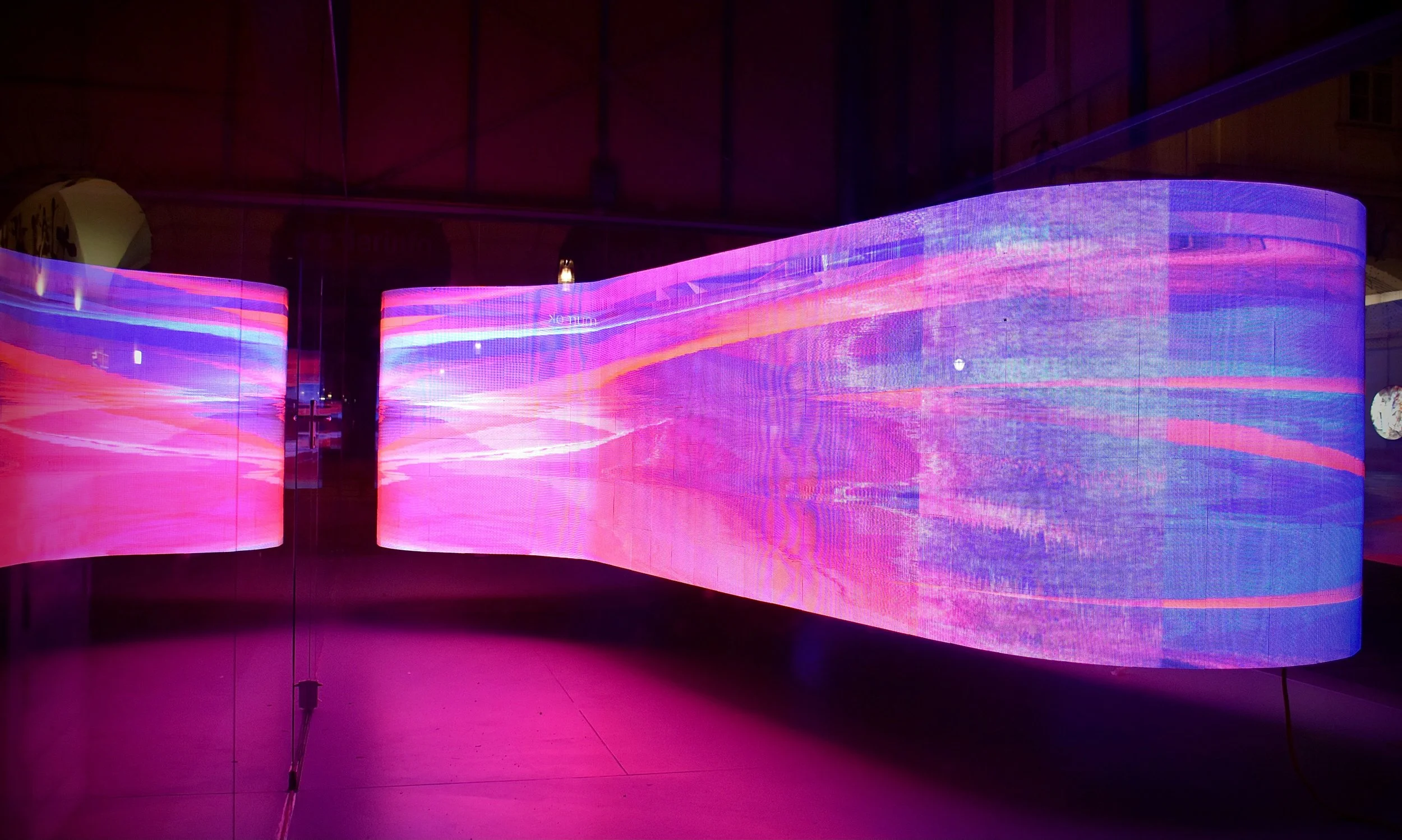 Curved LED screen displaying abstract purple and pink digital art, DOOH.