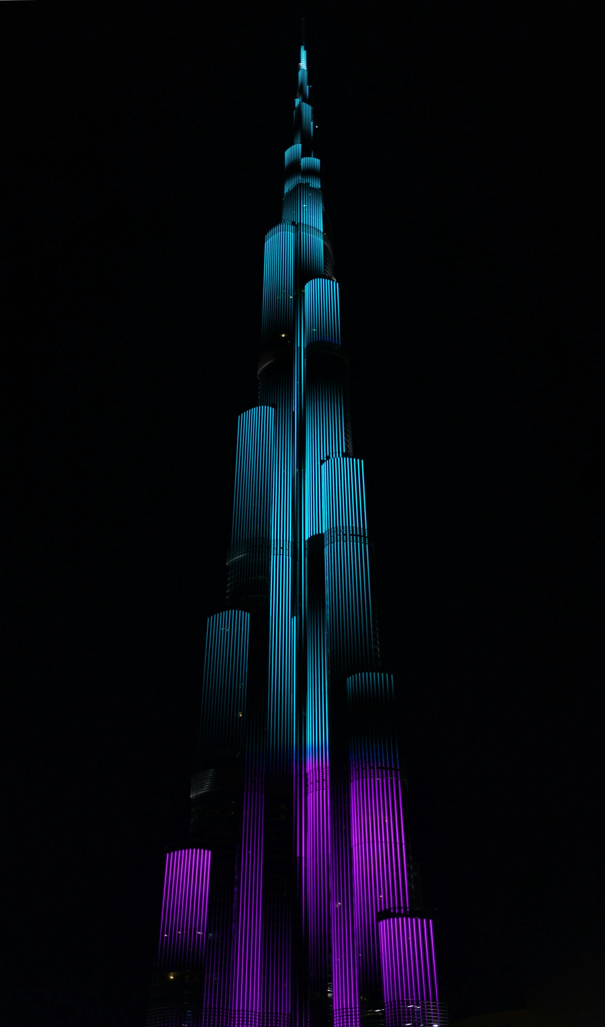 Burj Khalifa illuminated with blue and purple lights at night.