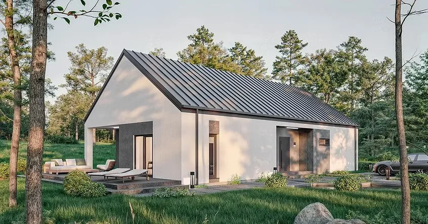 Modern white house with a gabled metal roof, on a grassy lot with trees, outdoor seating area, and a parked car.