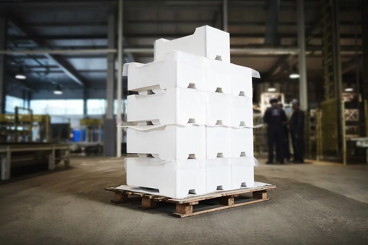 Stack of Styrofoam containers on a wooden pallet in a warehouse with two people in the background