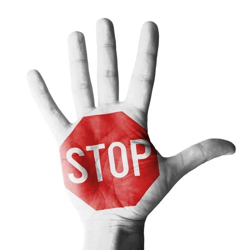 A black and white hand with a red stop sign overlay on the palm.