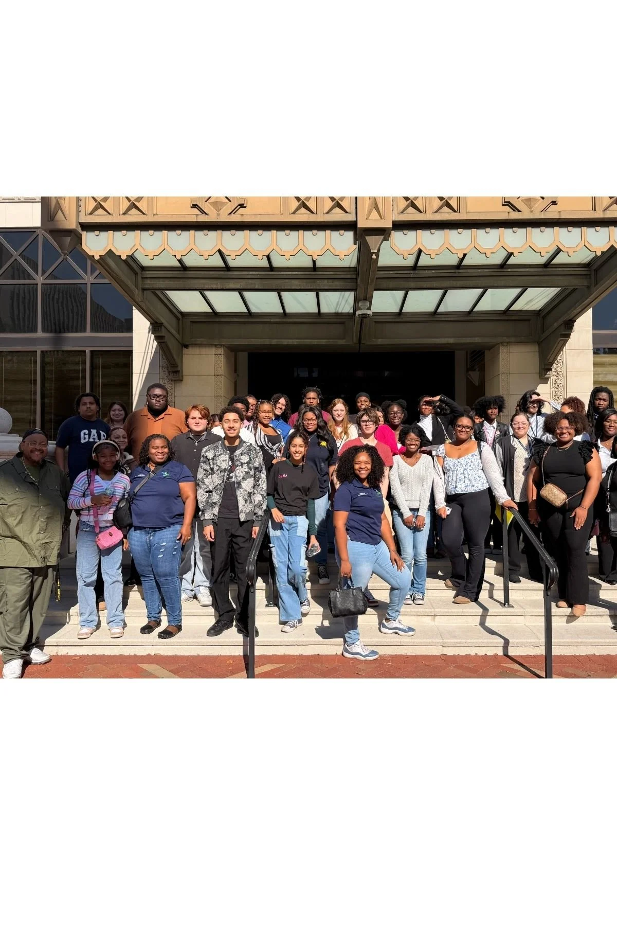 Group of diverse people standing on steps outside a building, posing for a photo.