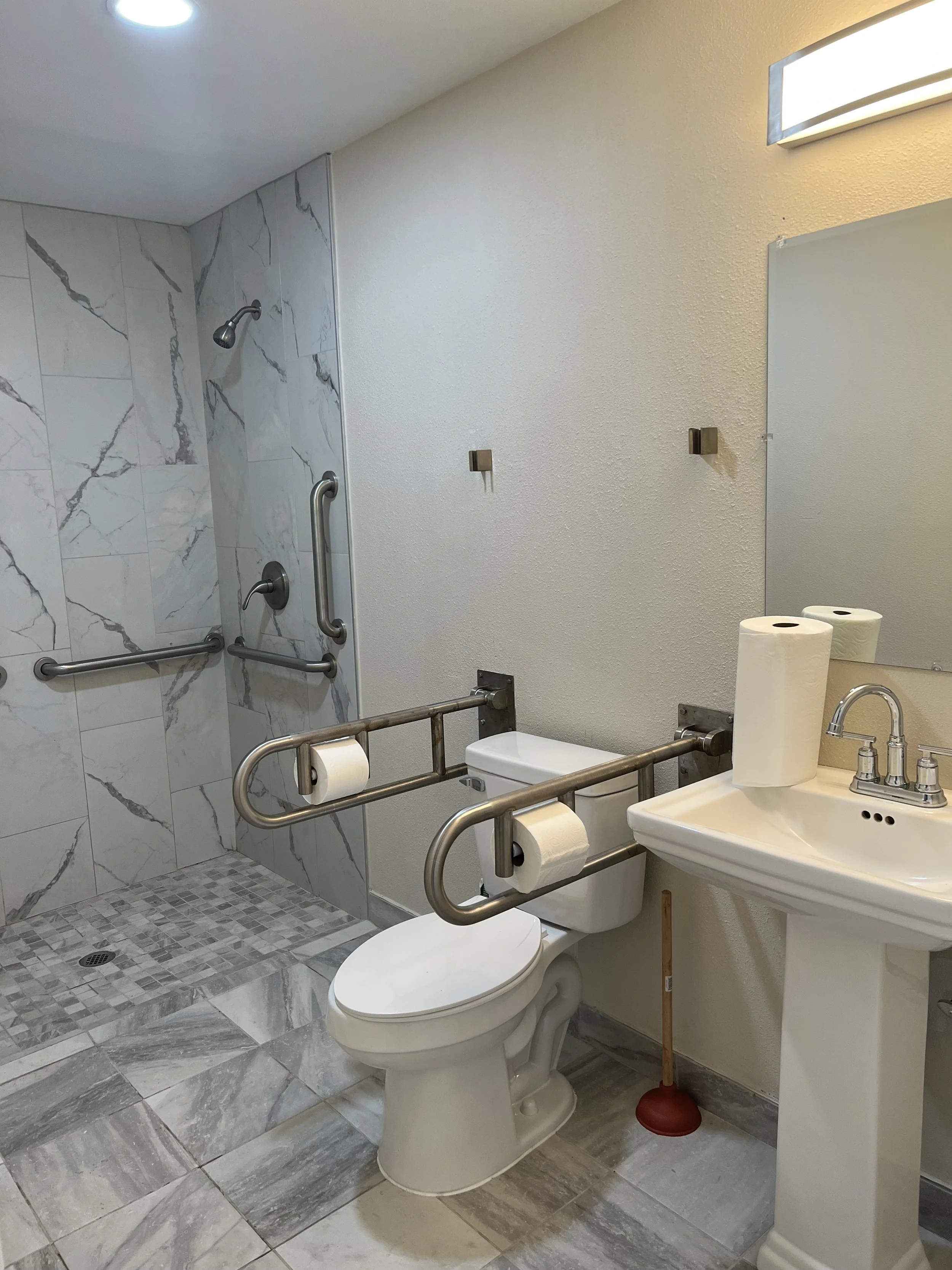 Accessible bathroom at Neighbors AFH Inc Adult Family Home in Tacoma, WA, featuring marble tiles, grab bars, and a safe, comfortable design for residents.