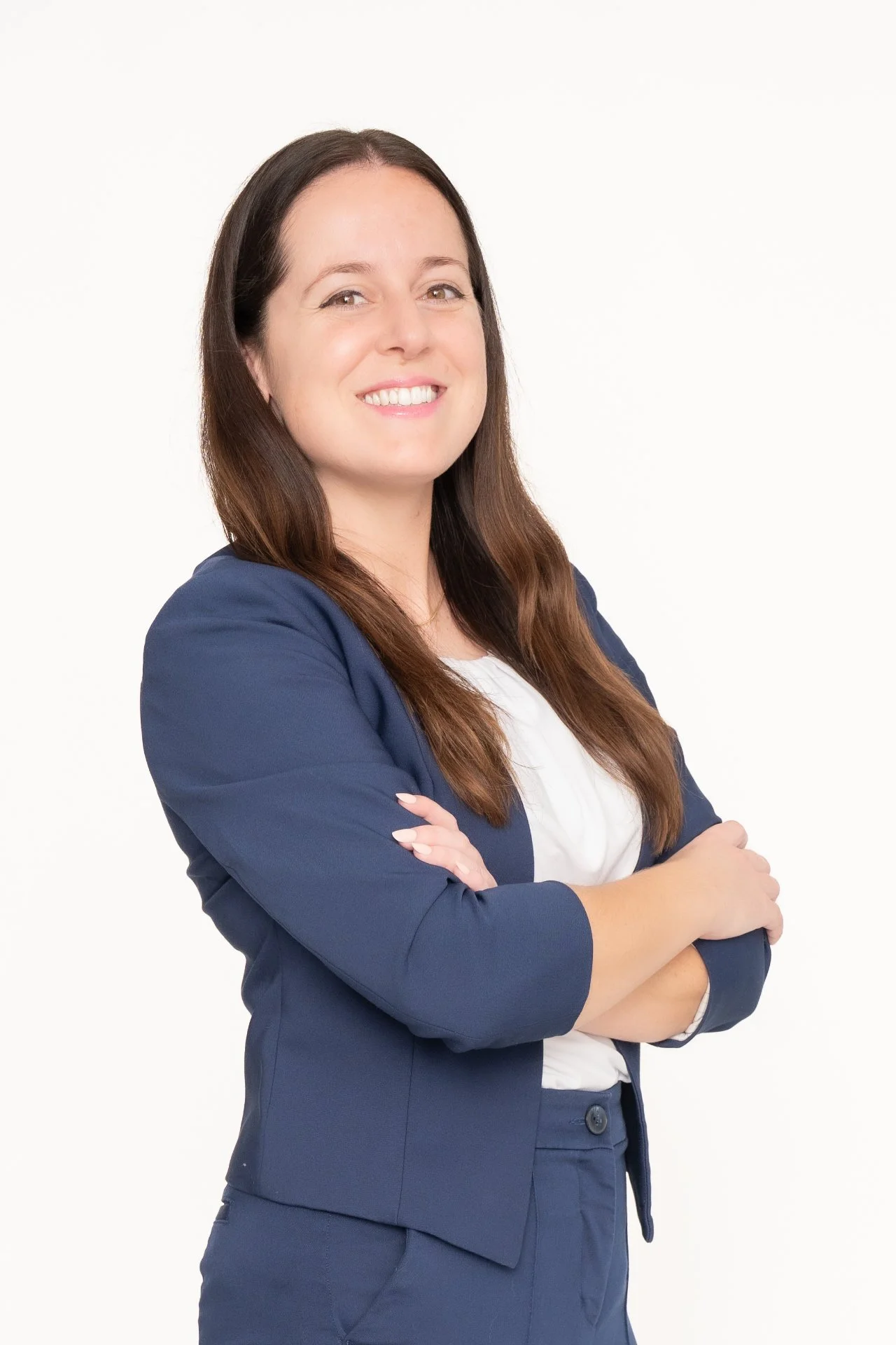 Wendy M. Brown wearing a navy blue blazer and matching pants, standing with arms crossed and smiling.