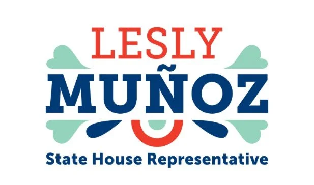 Campaign sign with the name 'Lesly Muñoz' in red and blue text, along with the title 'State House Representative' in smaller blue letters, decorated with stylized cloud and wave graphics.