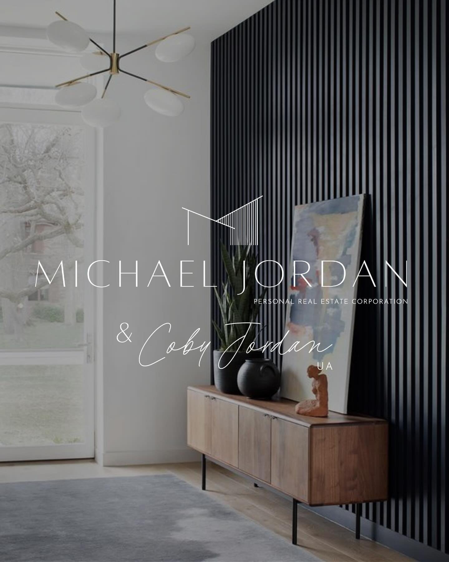 Modern living room with wooden sideboard, abstract painting, black striped accent wall, large window, light fixture, and gray rug.