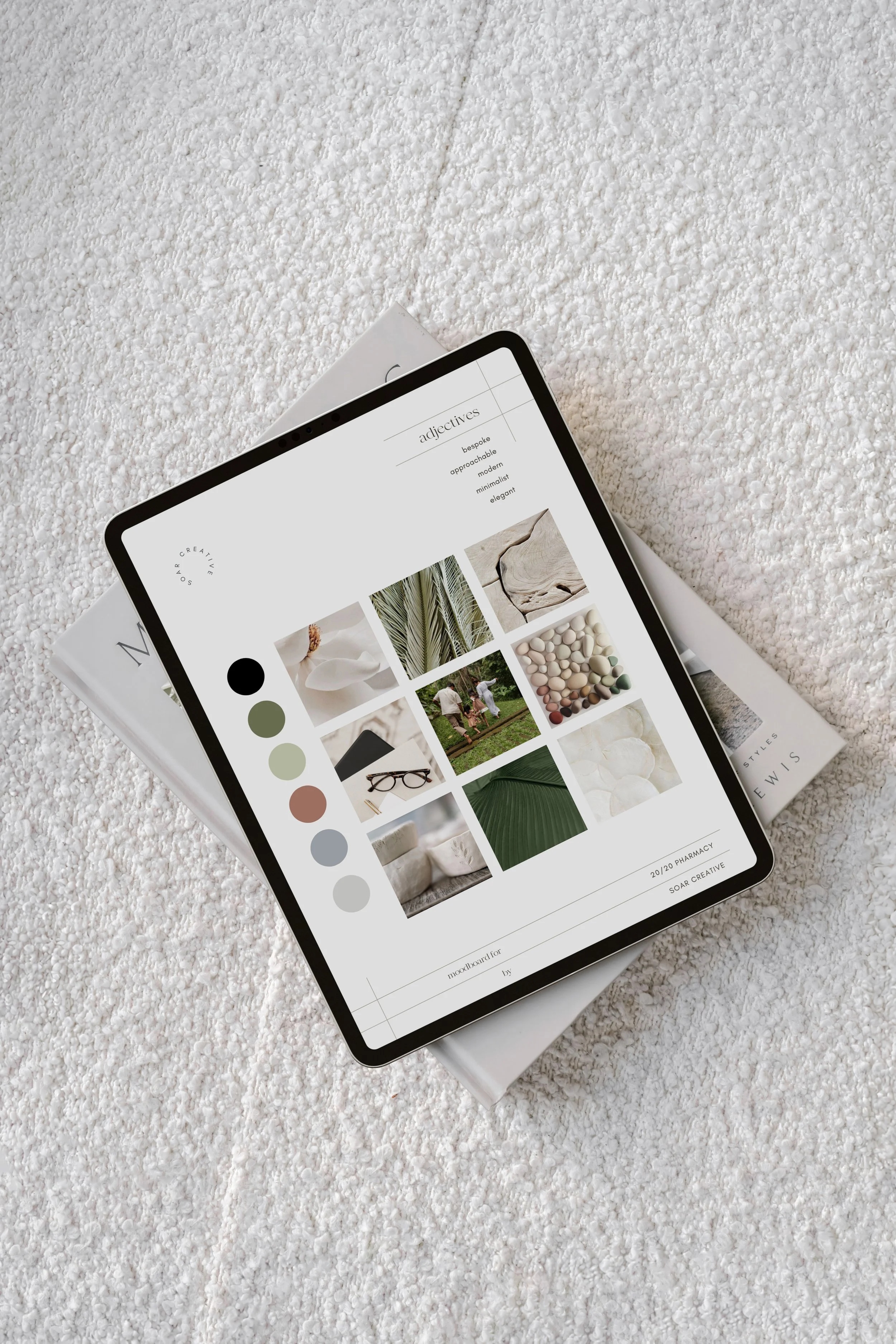 Tablet on a textured surface displaying a mood board with neutral colors, photos including natural elements and textiles, and color swatches.
