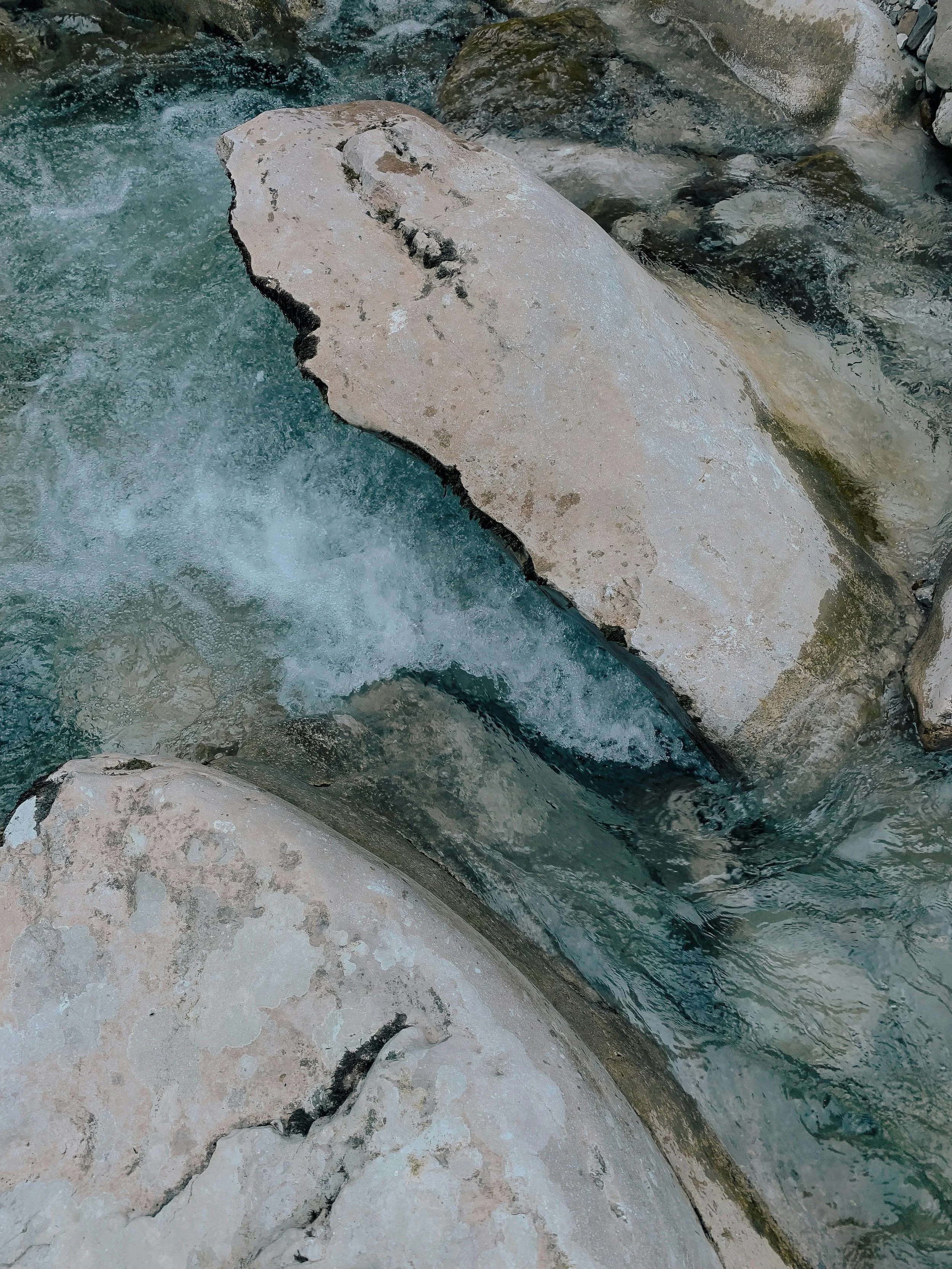 A close-up of a rocky shoreline with water flowing over the rocks in a stream or river.