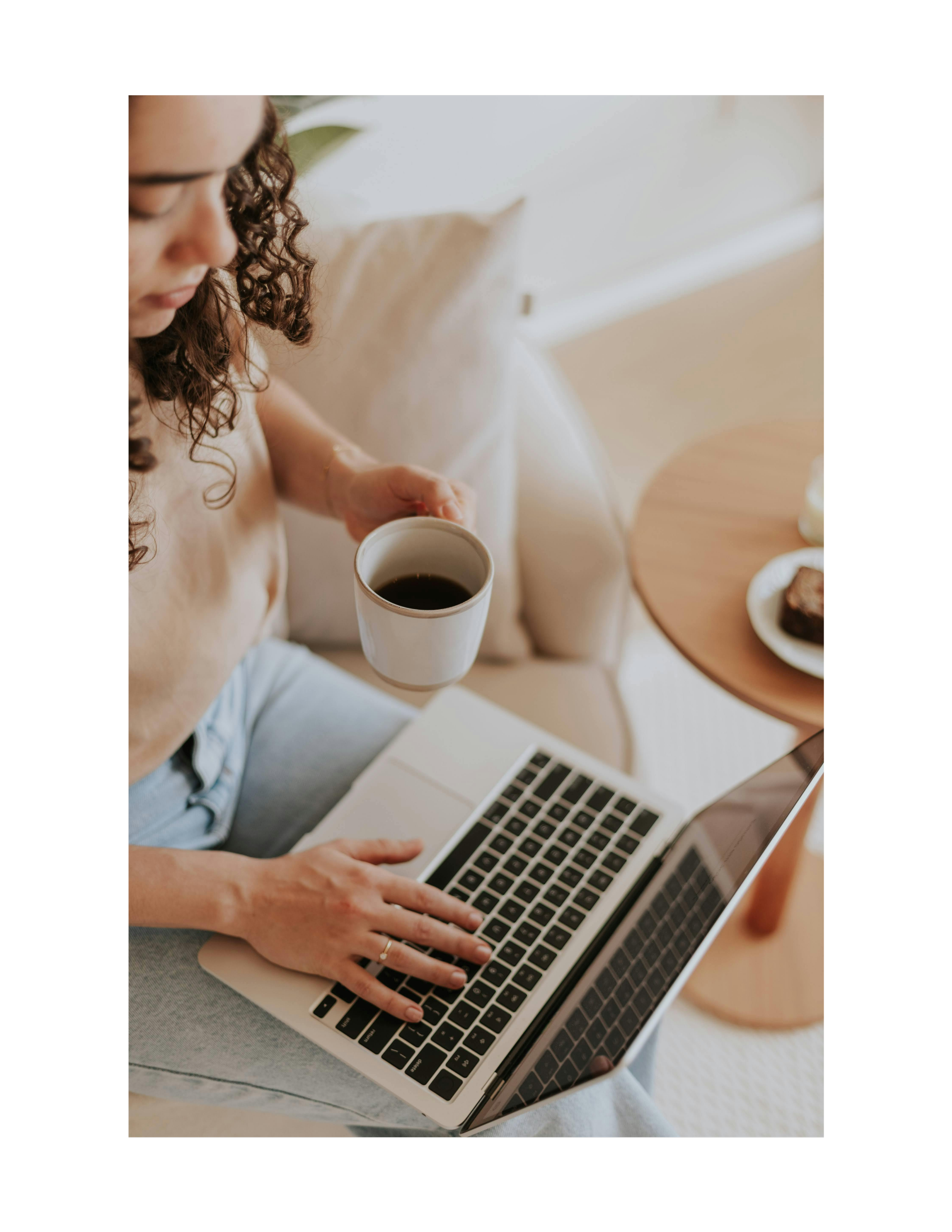 A woman working on a laptop with a cup of coffee nearby.