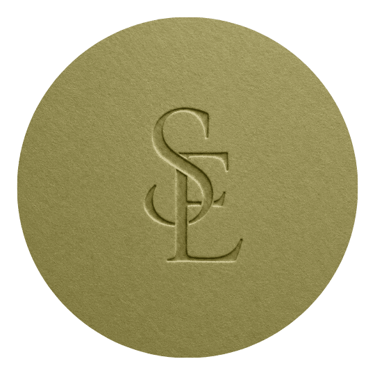 A circular, olive-green item with a sewn logo featuring the intertwined letters S, C, and L.