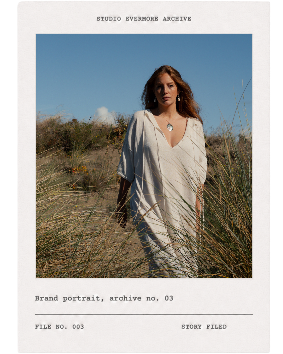 A woman in a cream-colored dress walking through tall grass on a sandy dune under a clear blue sky, with the text 'Studio Evermore Archive' at the top and a description indicating a brand portrait with archive number 03.
