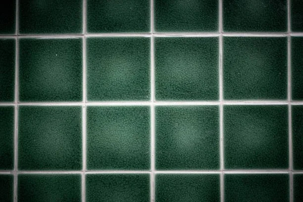 Close-up of green tiled wall with white grout lines.