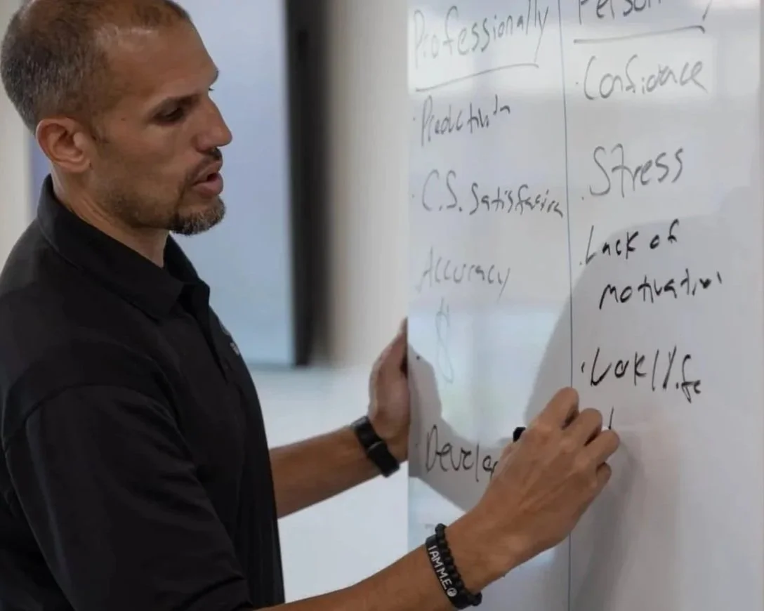 Man writing on a whiteboard during a meeting or class.