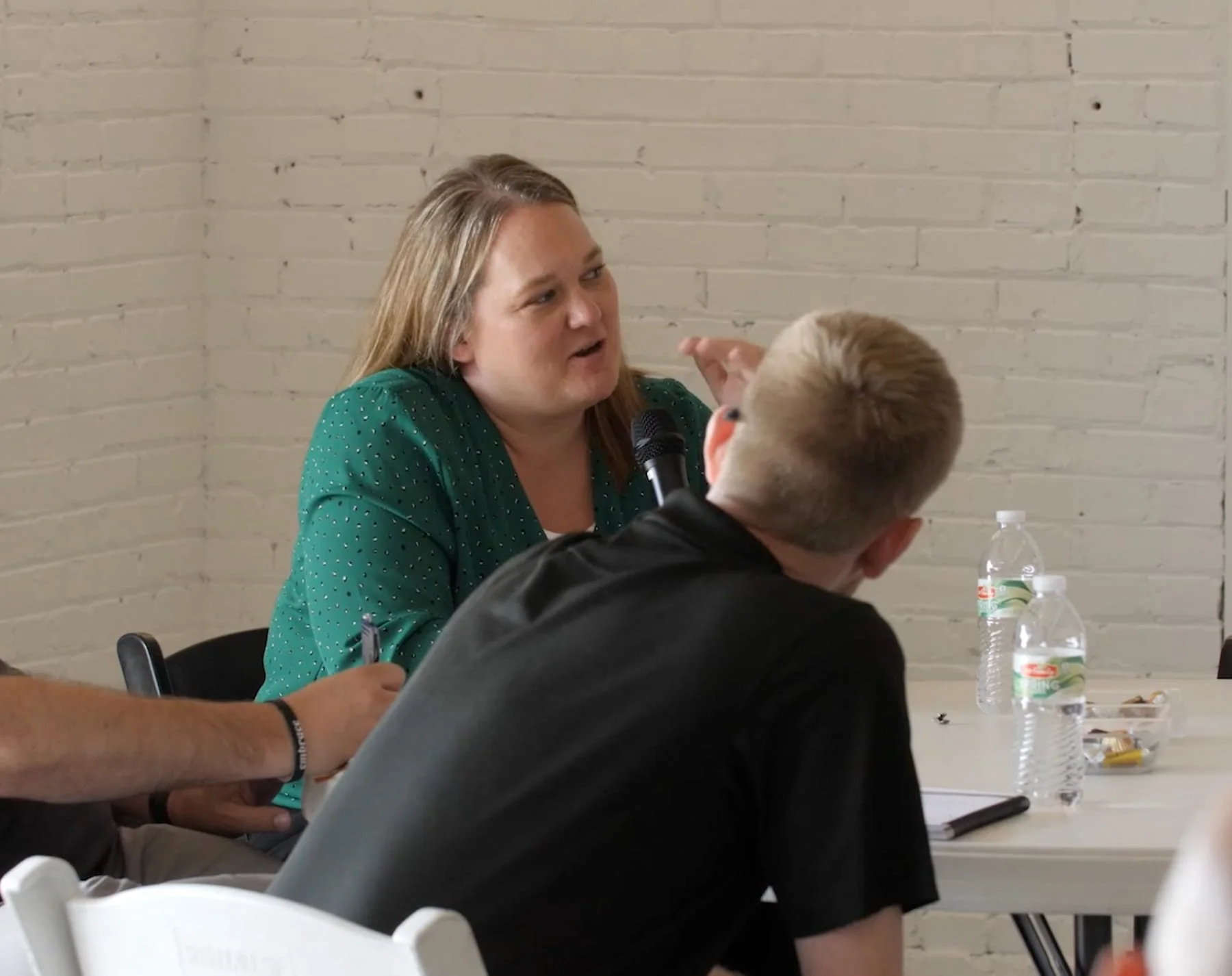 Woman talking to coworkers with microphone.