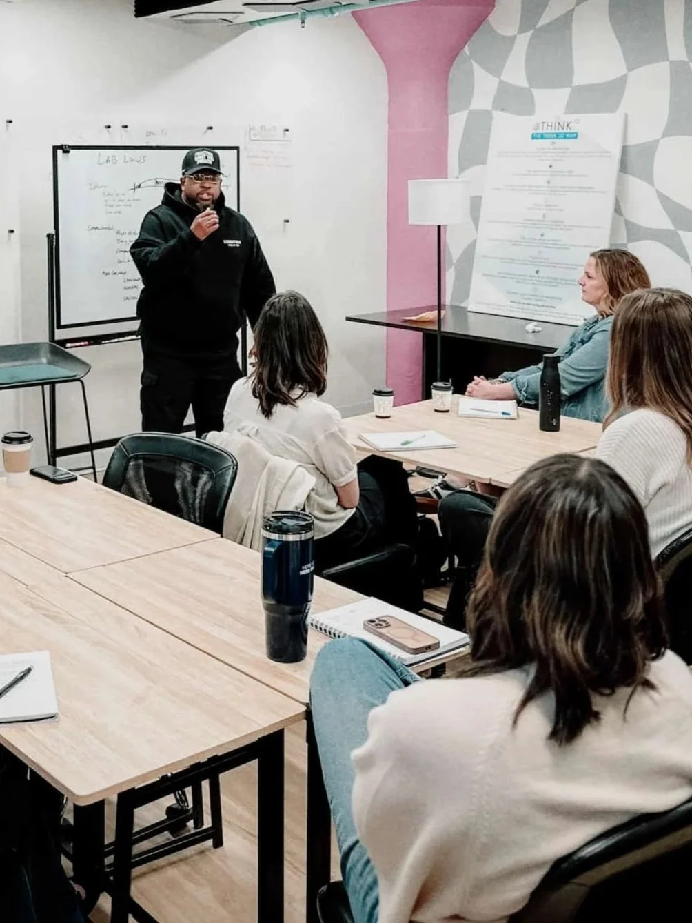 Vaney speaking to people in a classroom with a whiteboard