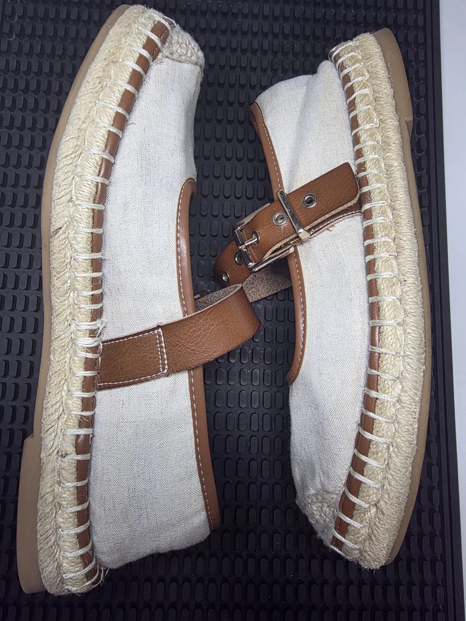 A pair of ice skates with white canvas material, brown leather accents, and beige fur lining, placed on a black textured surface.