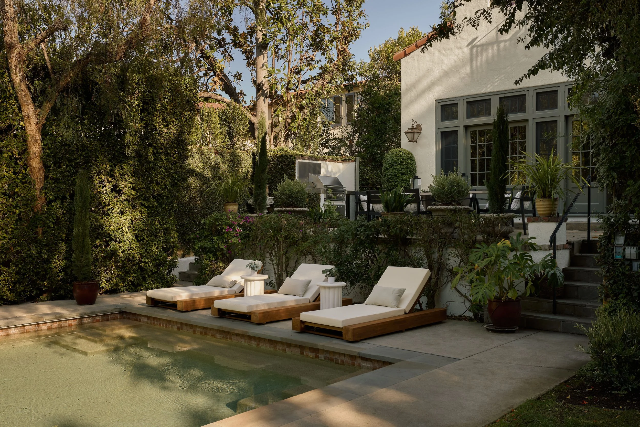 Outdoor pool terrace at a luxury Hancock Park residence in Los Angeles, staged by Francesca Grace with resort-style lounge seating and landscaped gardens.
