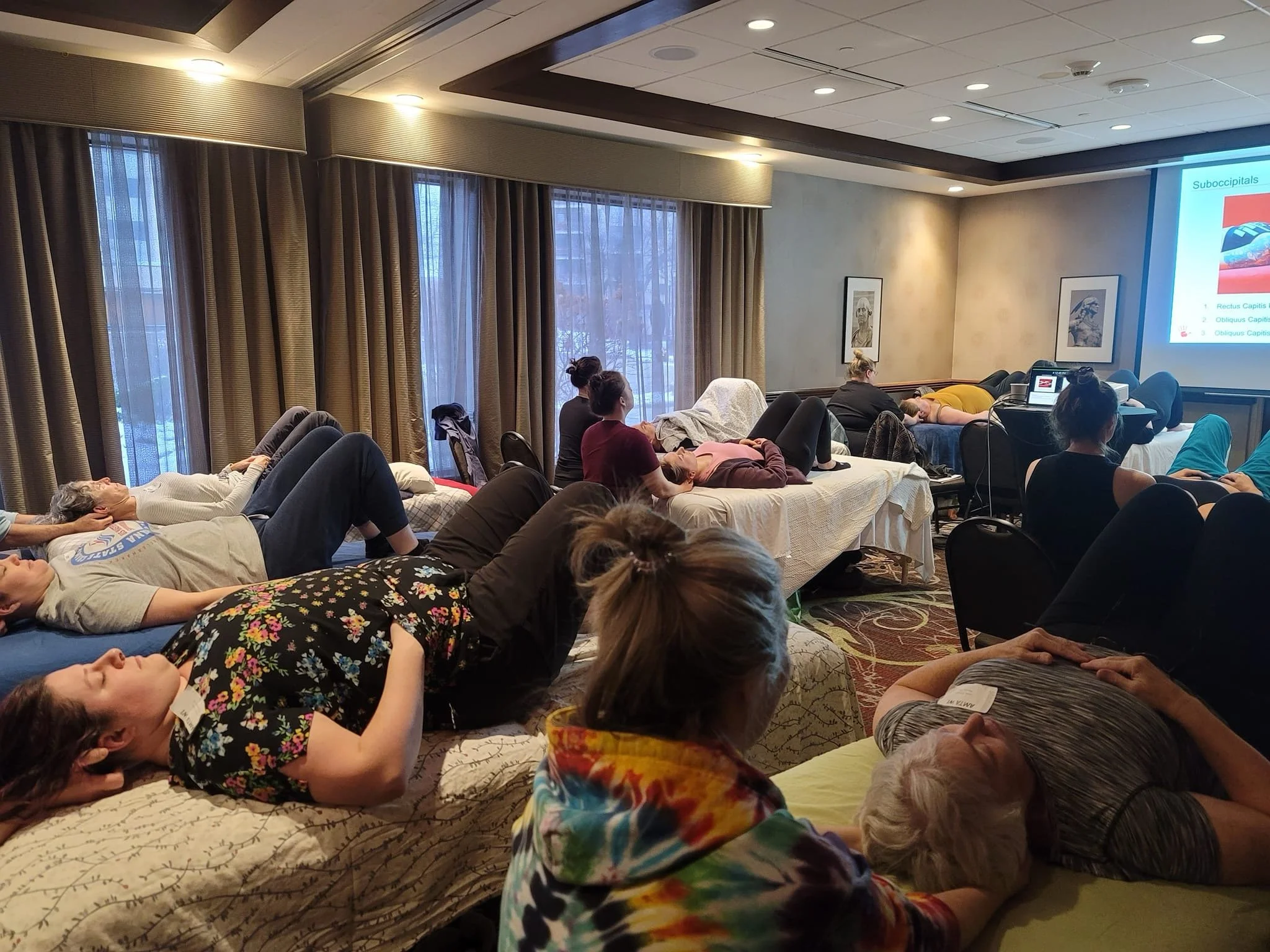People participating in a relaxation or meditation session in a conference room, lying on mattresses with their eyes closed.