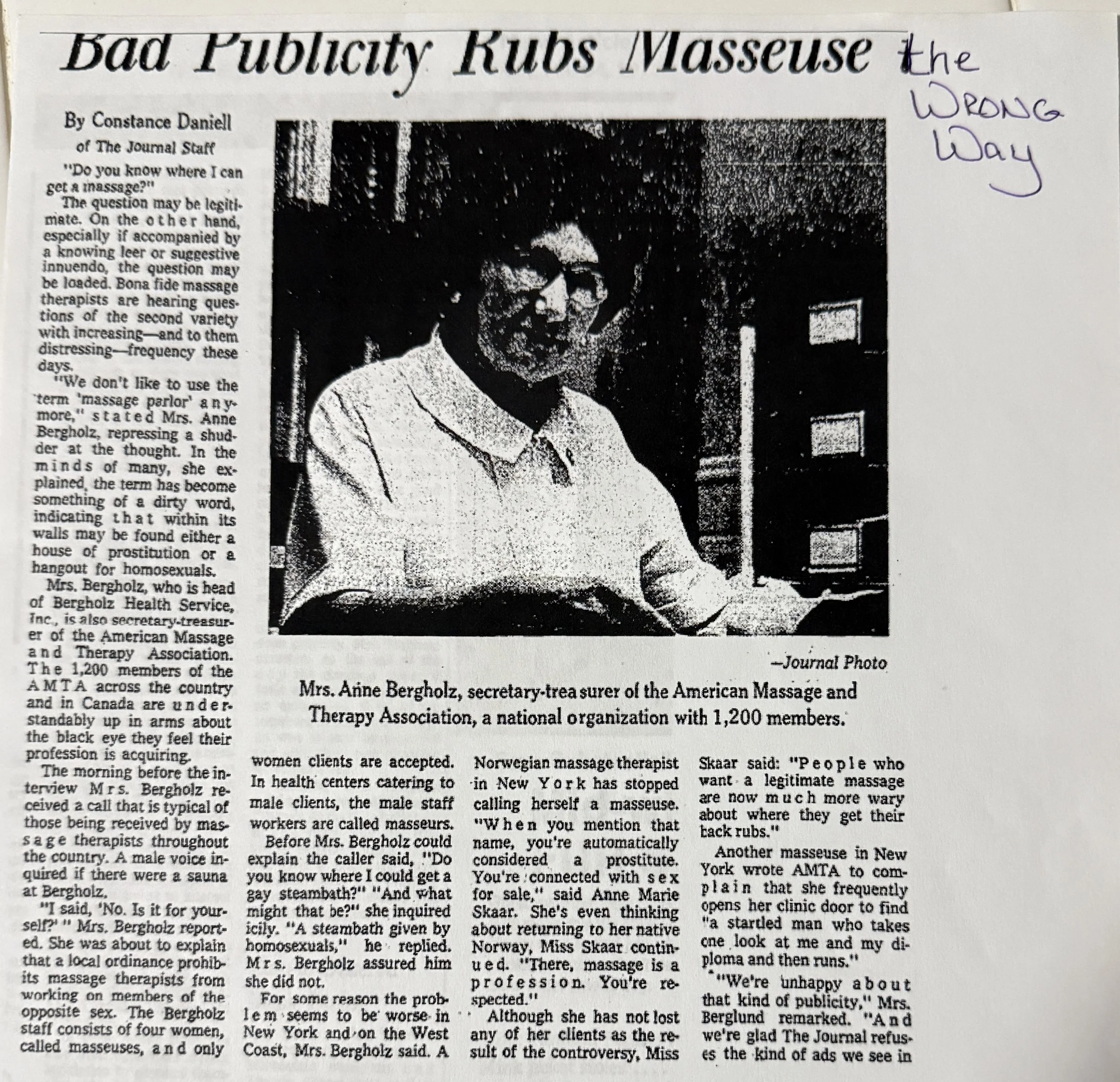 A black and white newspaper article with a photo of a woman wearing glasses and a beard. The headline reads 'Bad Publicity Rubs Masseuse the Wrong Way' and there is handwritten note in purple ink on the right side that says 'the WRONG way'.