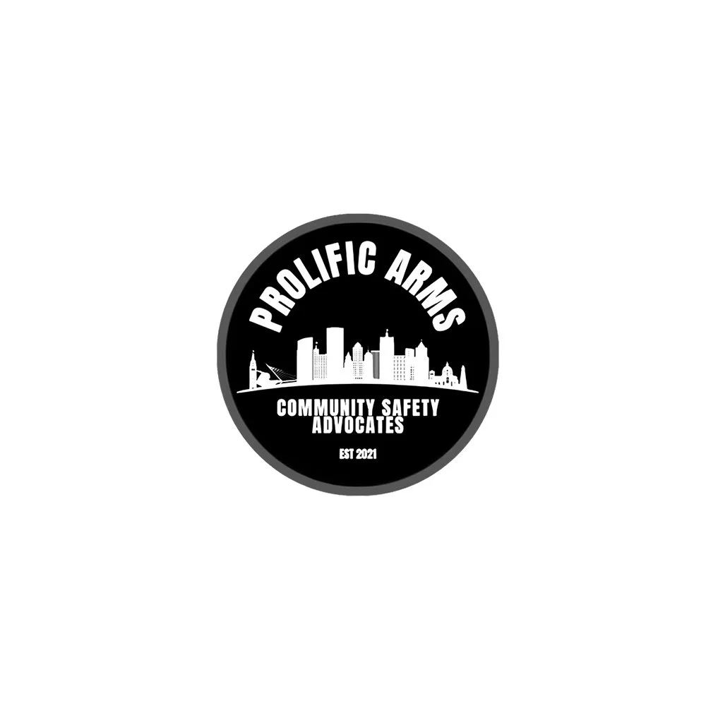 A circular logo with the text 'Prolific Arms' at the top, a skyline silhouette of a city in the middle, and 'Community Safety Advocates' with 'Est 2021' below, all on a black background.