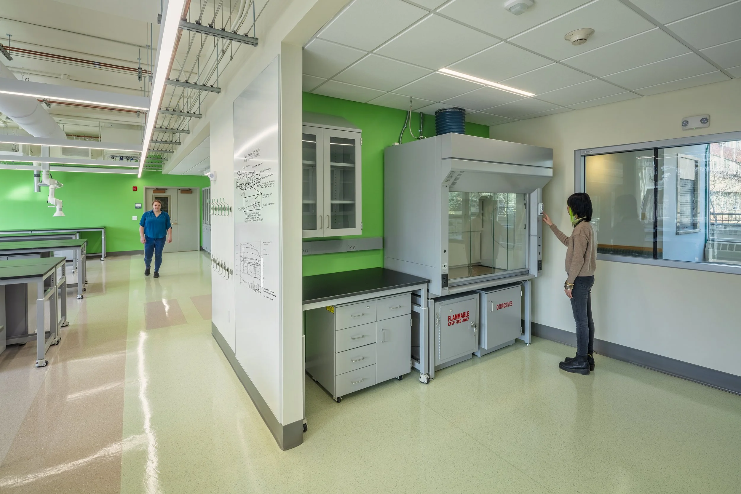 Researcher using a laboratory fume hood in a Cornell University science lab.