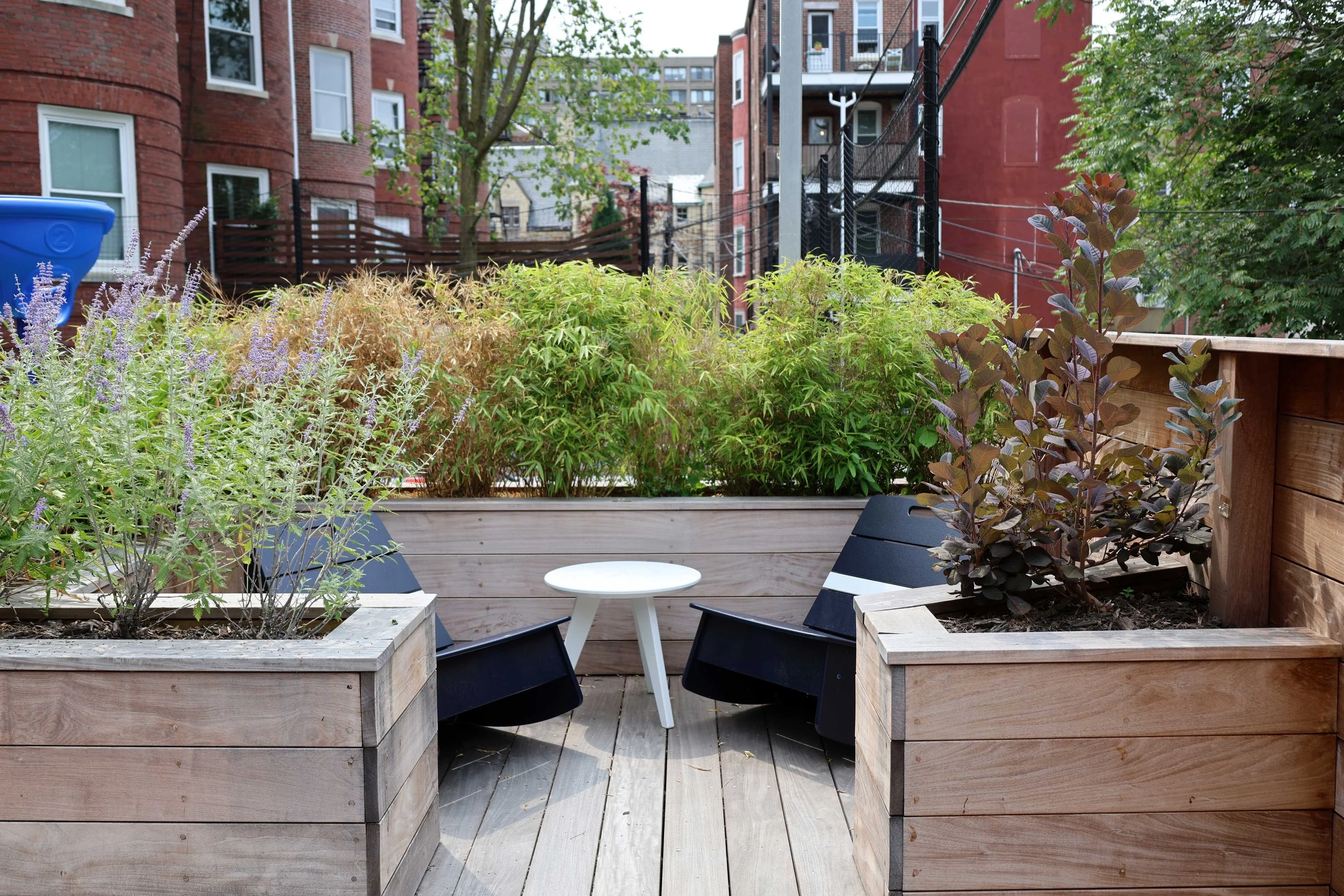 Outdoor therapeutic space with lounge chairs nestled among raised wood planters and surrounding greenery.