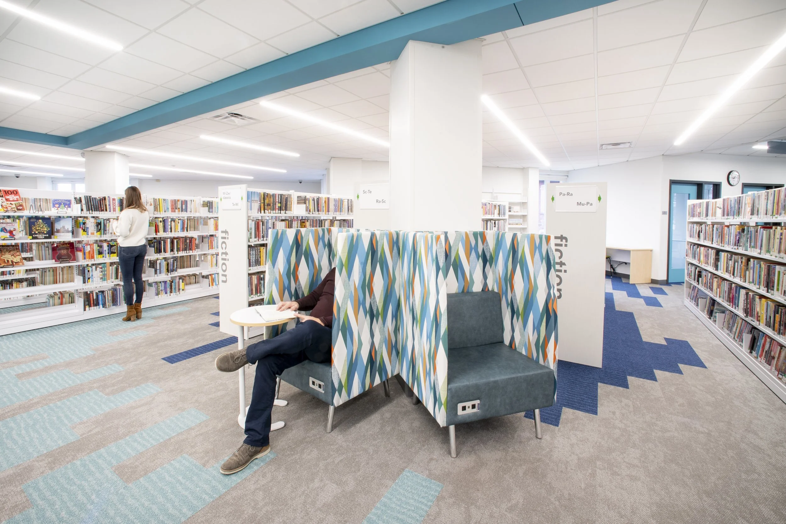 Library interior with bookshelves and patterned high-back study seating designed for individual reading or work.