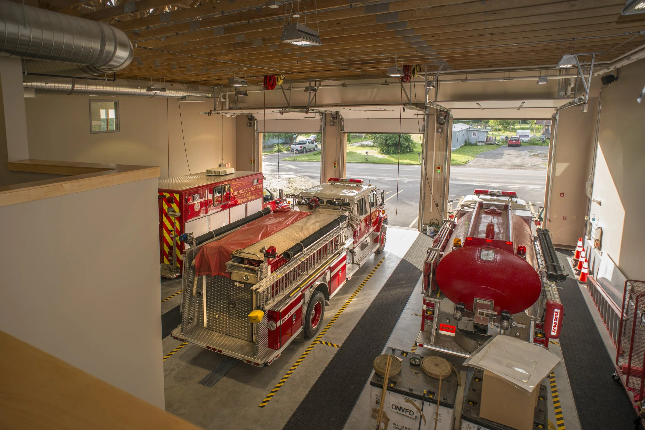Fire station apparatus bay with fire engines, emergency response vehicles, and high-bay garage designed for rapid deployment.