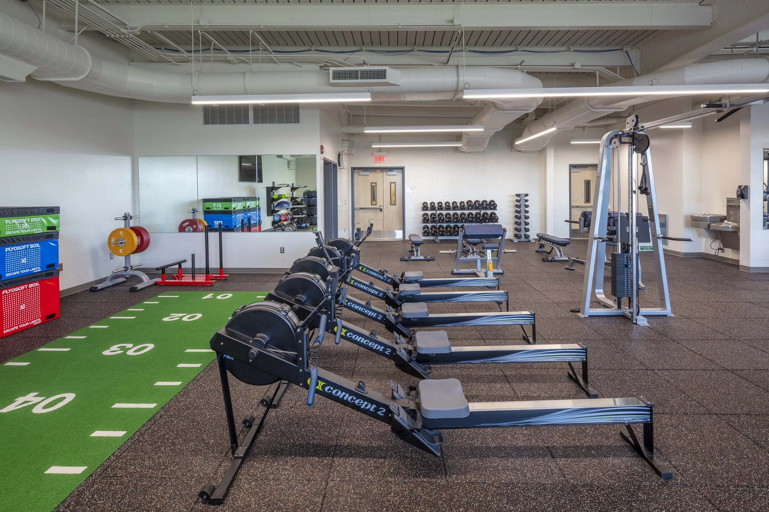 Fitness center with rowing machines, free weights, strength equipment, and indoor training turf.