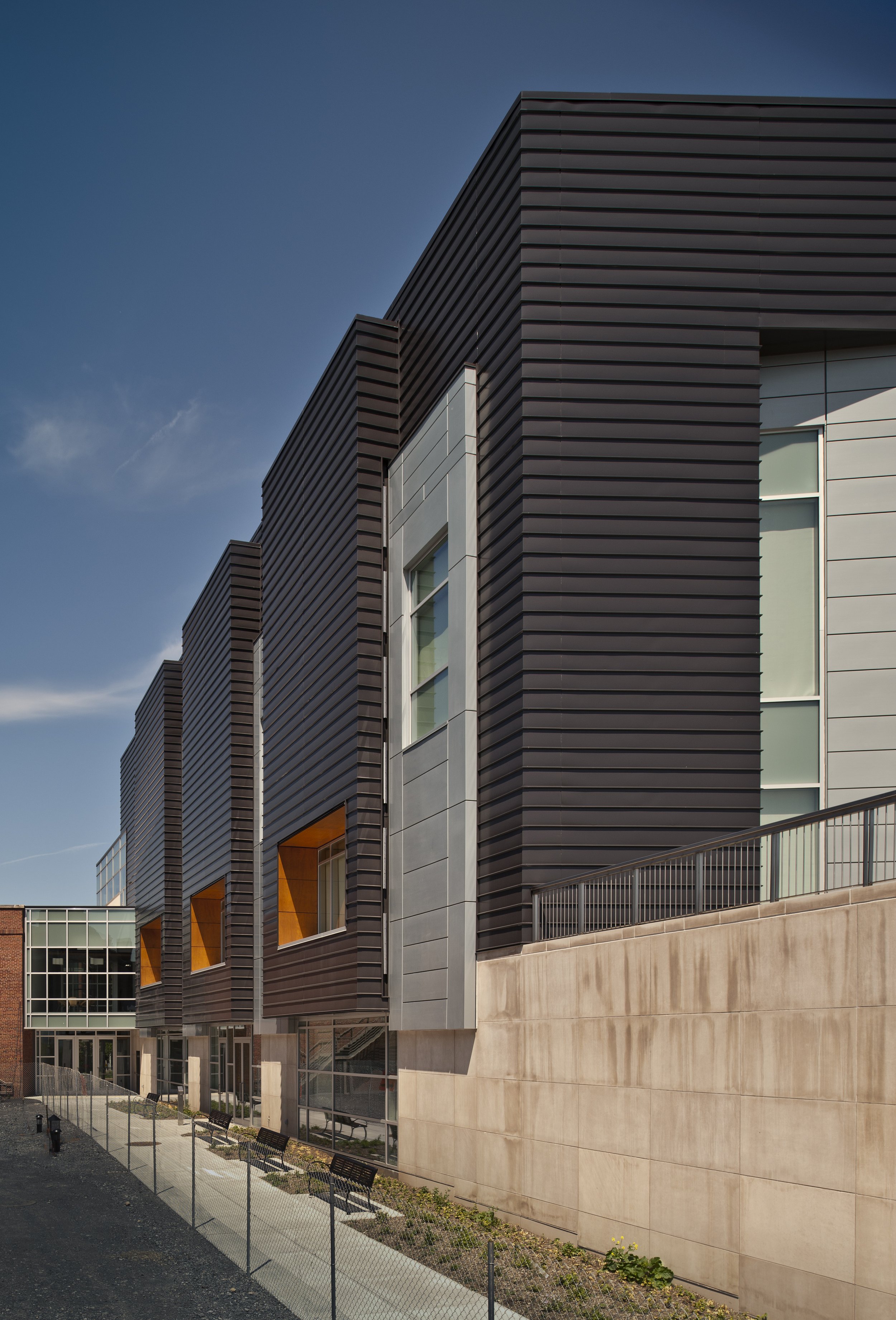 Exterior view of the Le Moyne College Coyne Science Center Addition featuring contemporary metal panel cladding, recessed windows, and a pedestrian walkway.