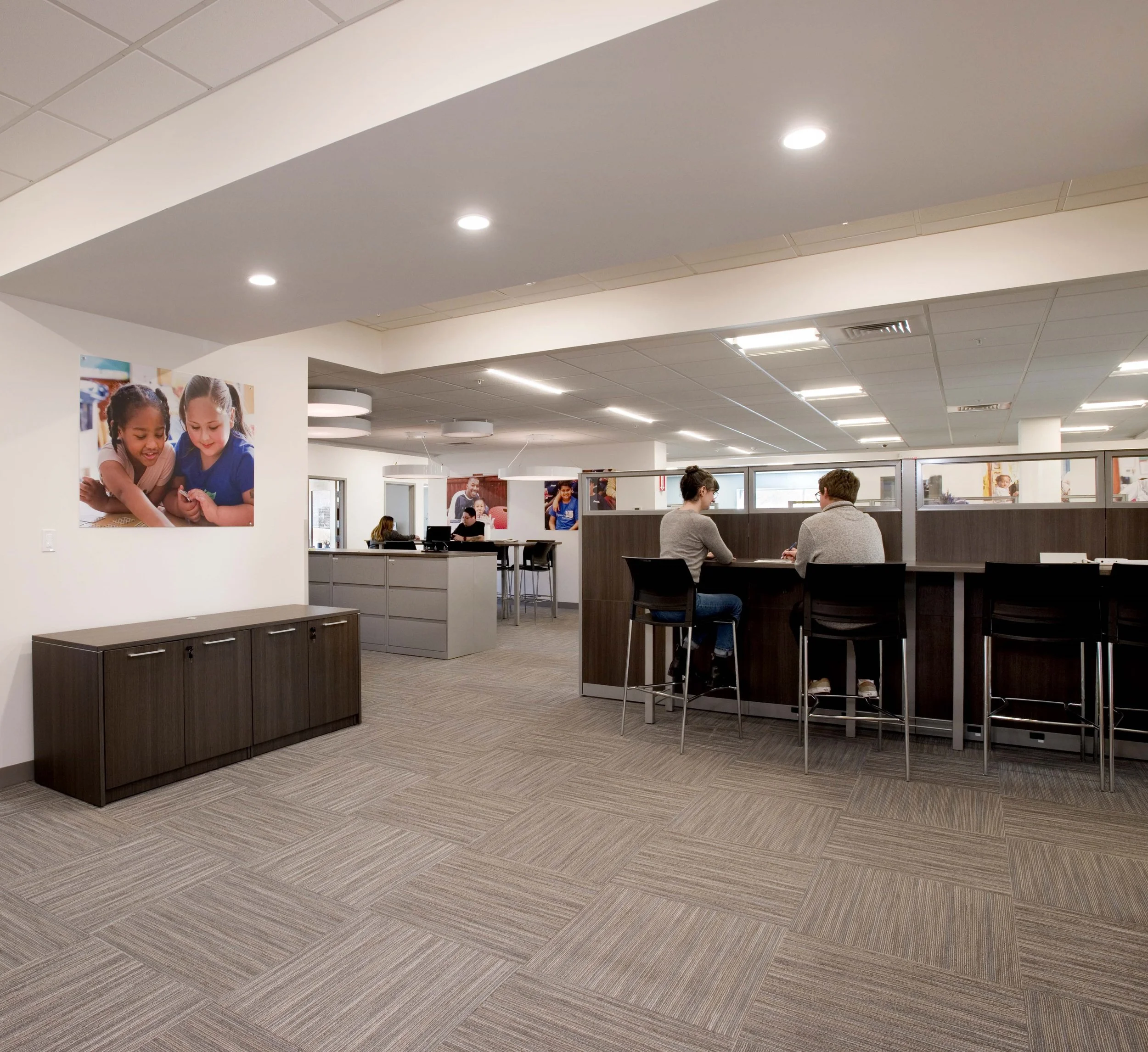 Open staff workspace with high-top tables, workstations, and collaborative seating in a modern early education center.