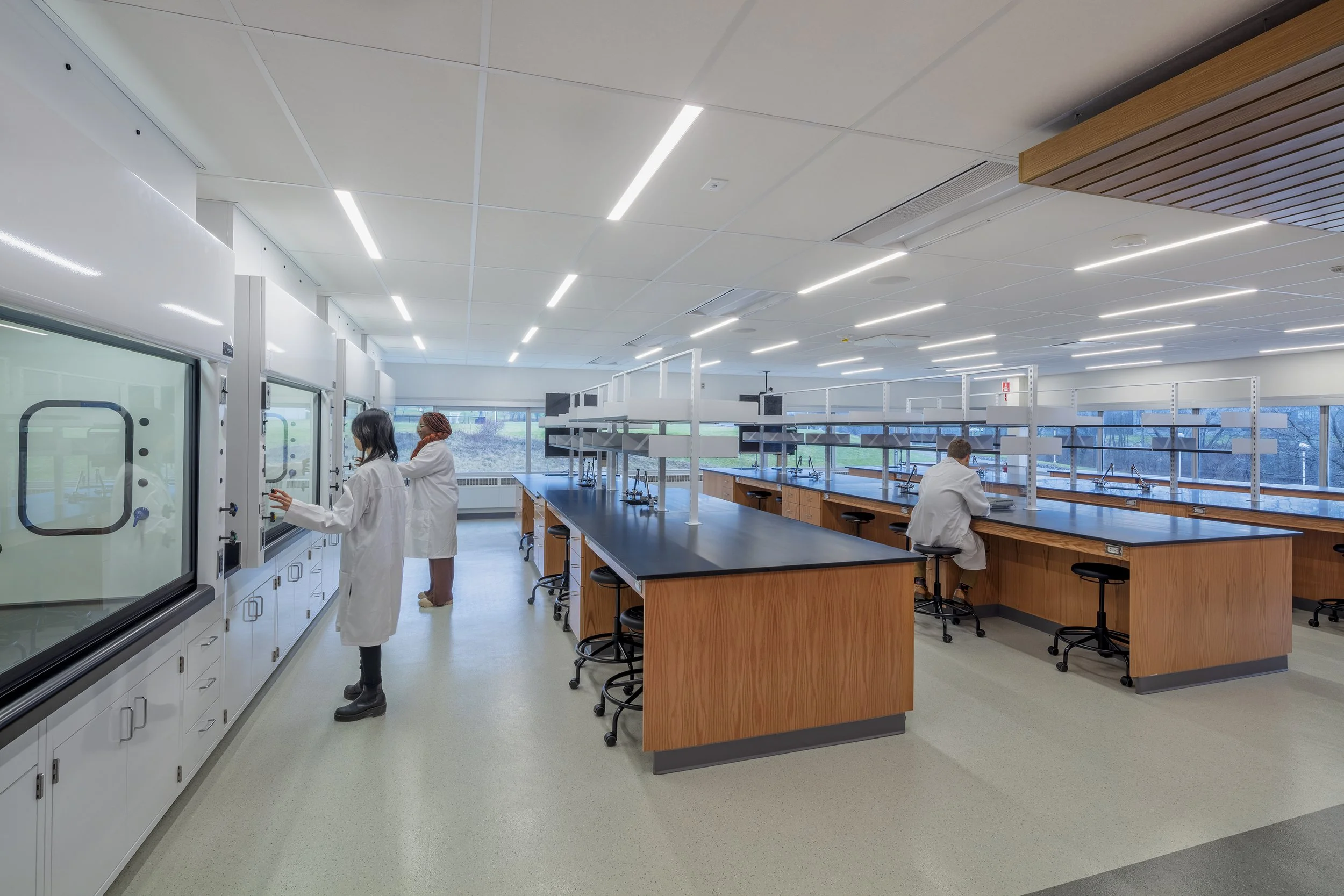 Science laboratory with fixed lab benches, fume hoods, integrated utilities, and perimeter workstations.