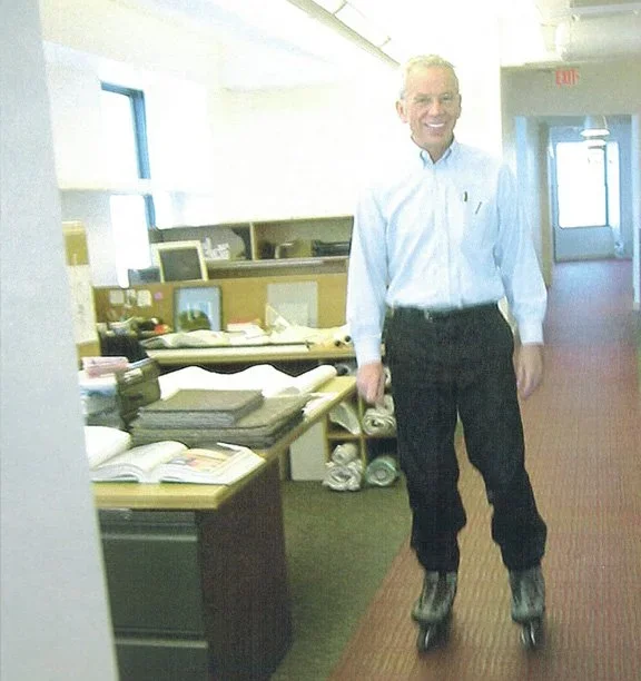 Man in business casual attire on roller skates in office corridor