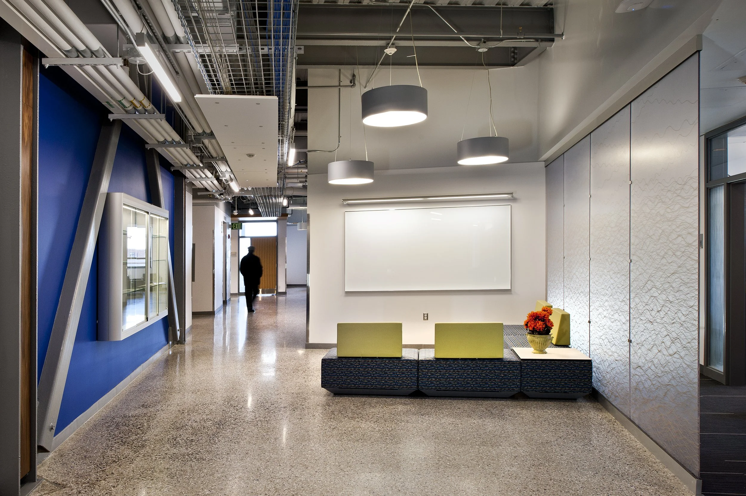 Interior corridor with informal seating, exposed structure, writable wall, and collaborative learning spaces.