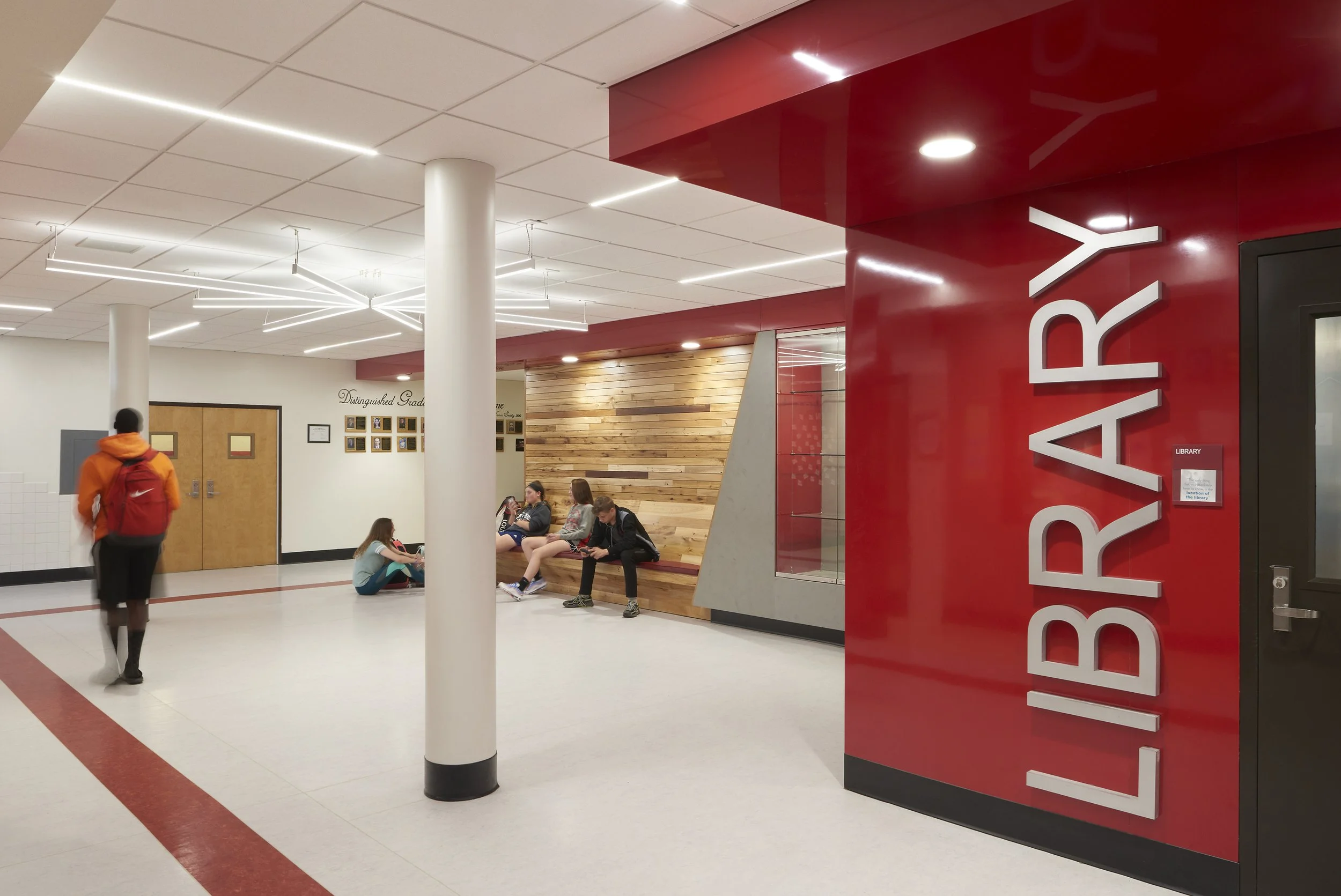 Library entrance and collaborative student commons with integrated wood seating and modern lighting.