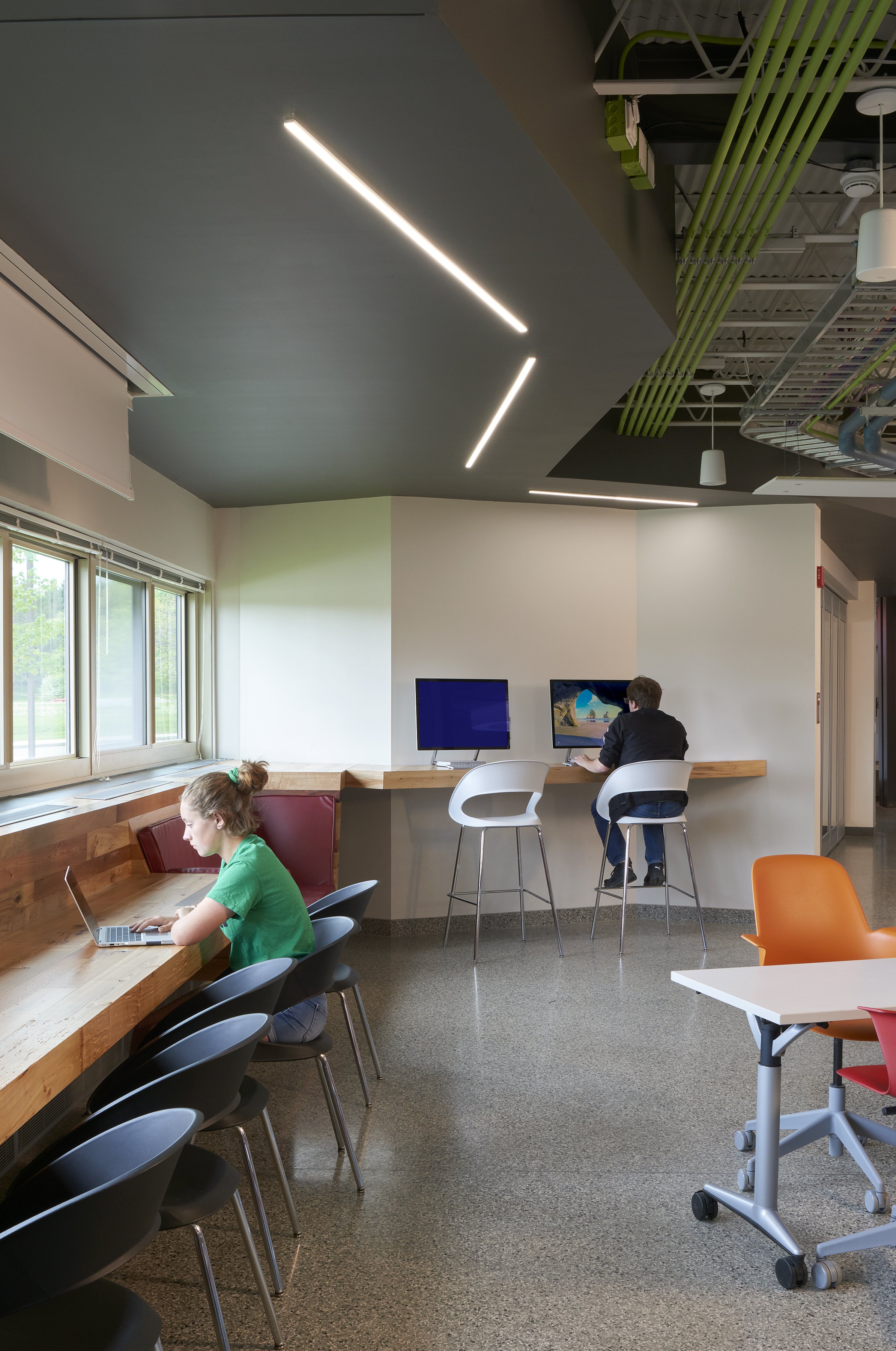 Students using individual computer workstations and window seating in the STEAM Learning Center.