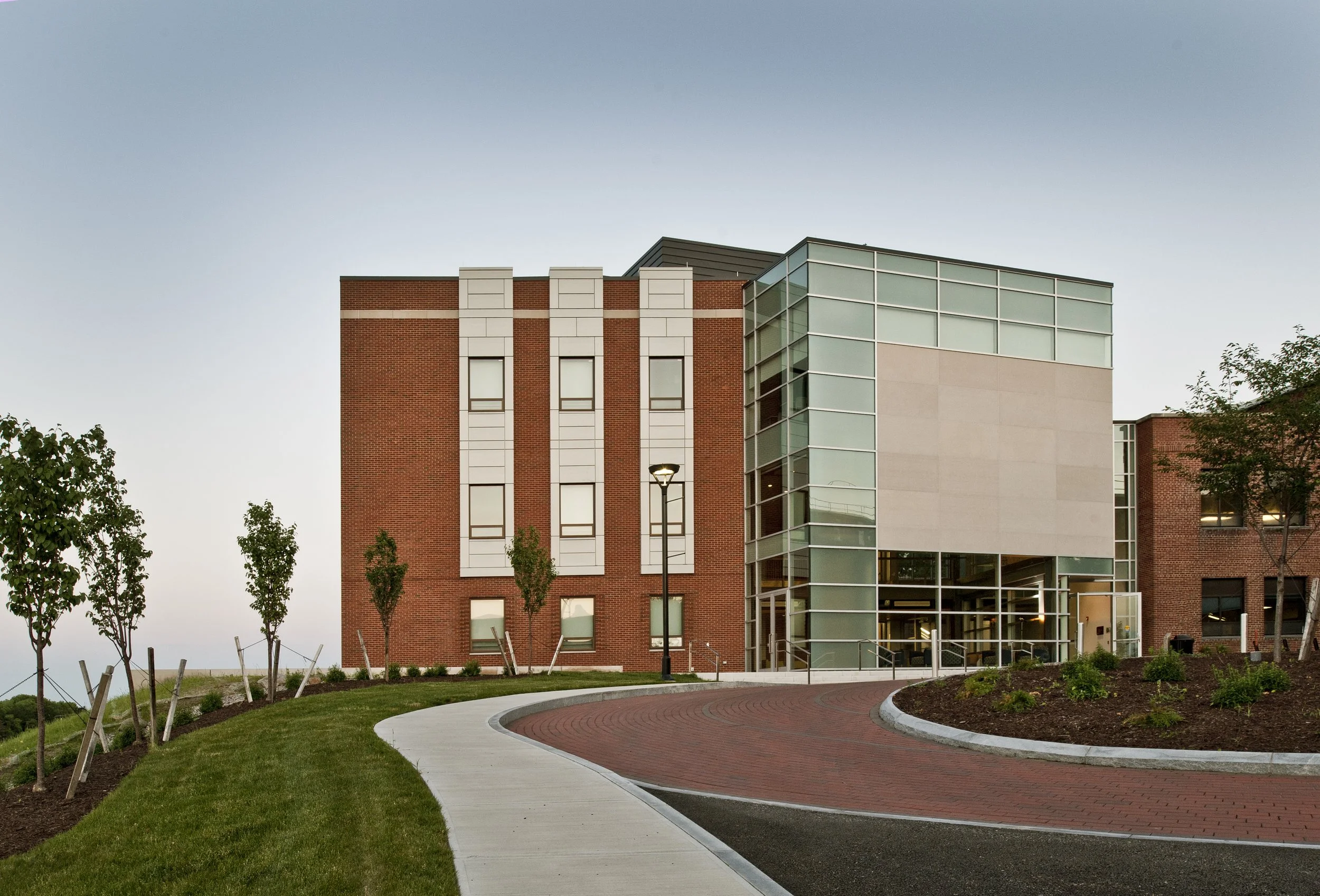 Main entrance to the Coyne Science Center Addition with a glass lobby, brick façade, landscaped grounds, and circular drop-off drive.
