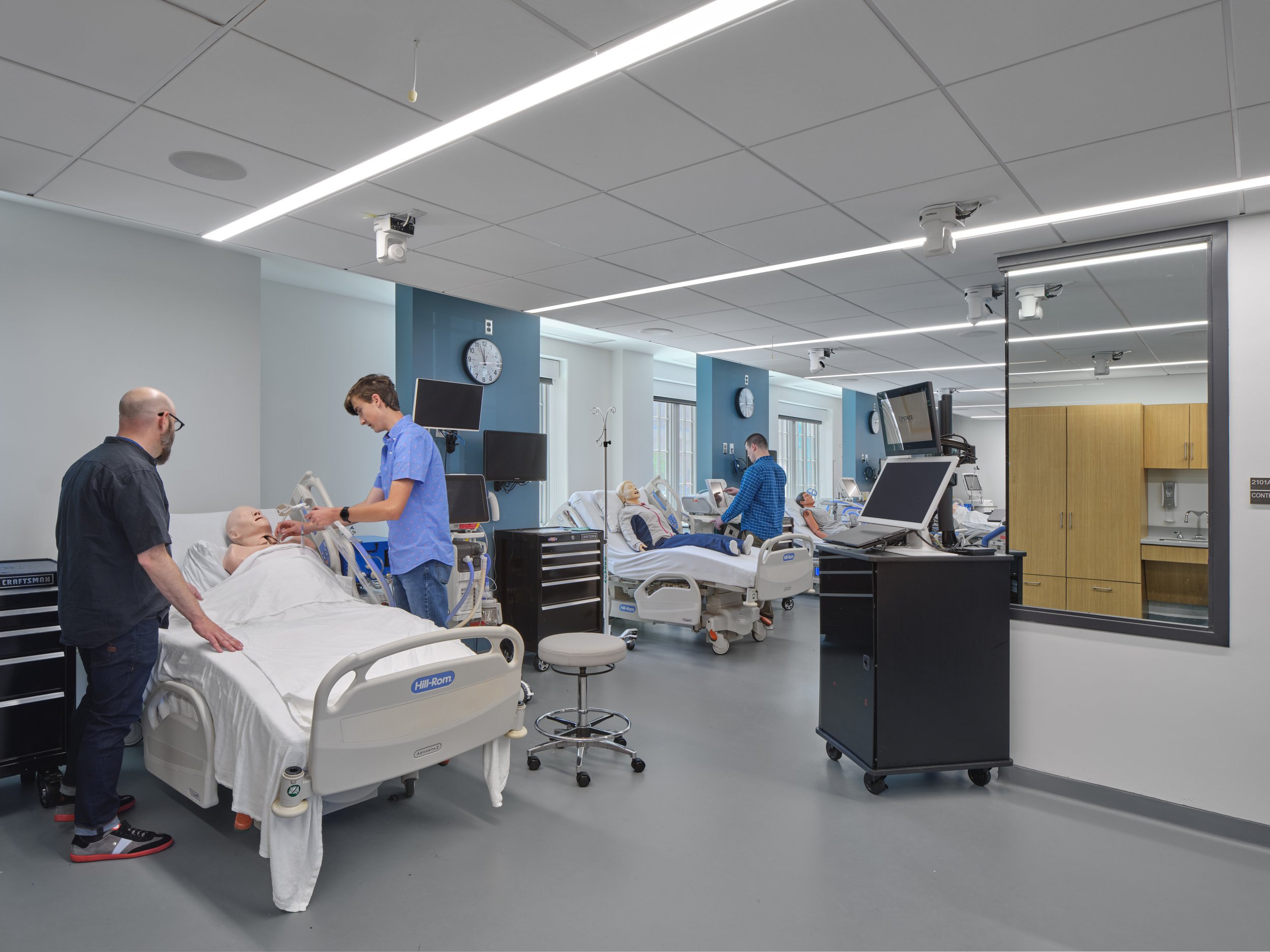 Healthcare simulation lab at SUNY Upstate Medical University's College of Health Professions where students train using hospital beds, medical equipment, and patient manikins.