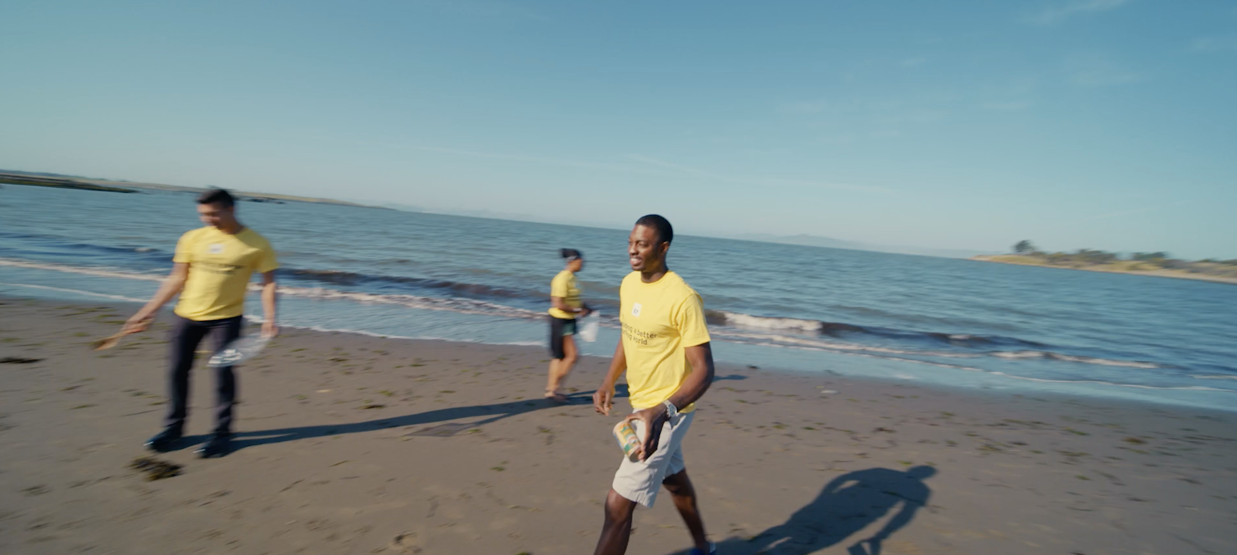 People in yellow shirts walking along the beach near the ocean