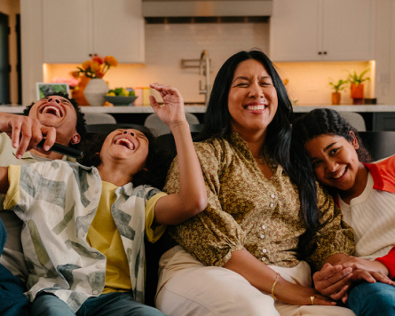 Four people sitting together in a kitchen, laughing and smiling happily.