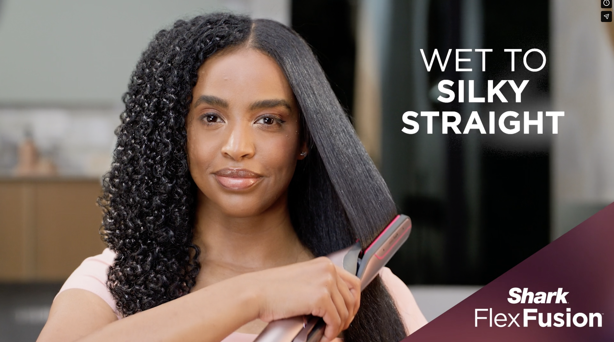 A woman with curly hair holding an electric hair straightening brush while looking at the camera, with text overlay promoting Wet to Silky Straight and Flex Fusion by Shark.