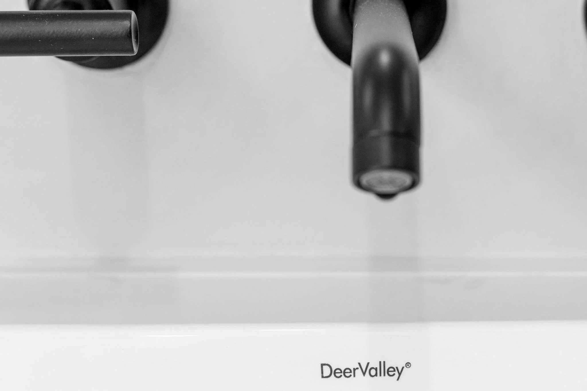 Close-up of a black faucet and part of a sink, with the brand name Deer Valley visible at the bottom.
