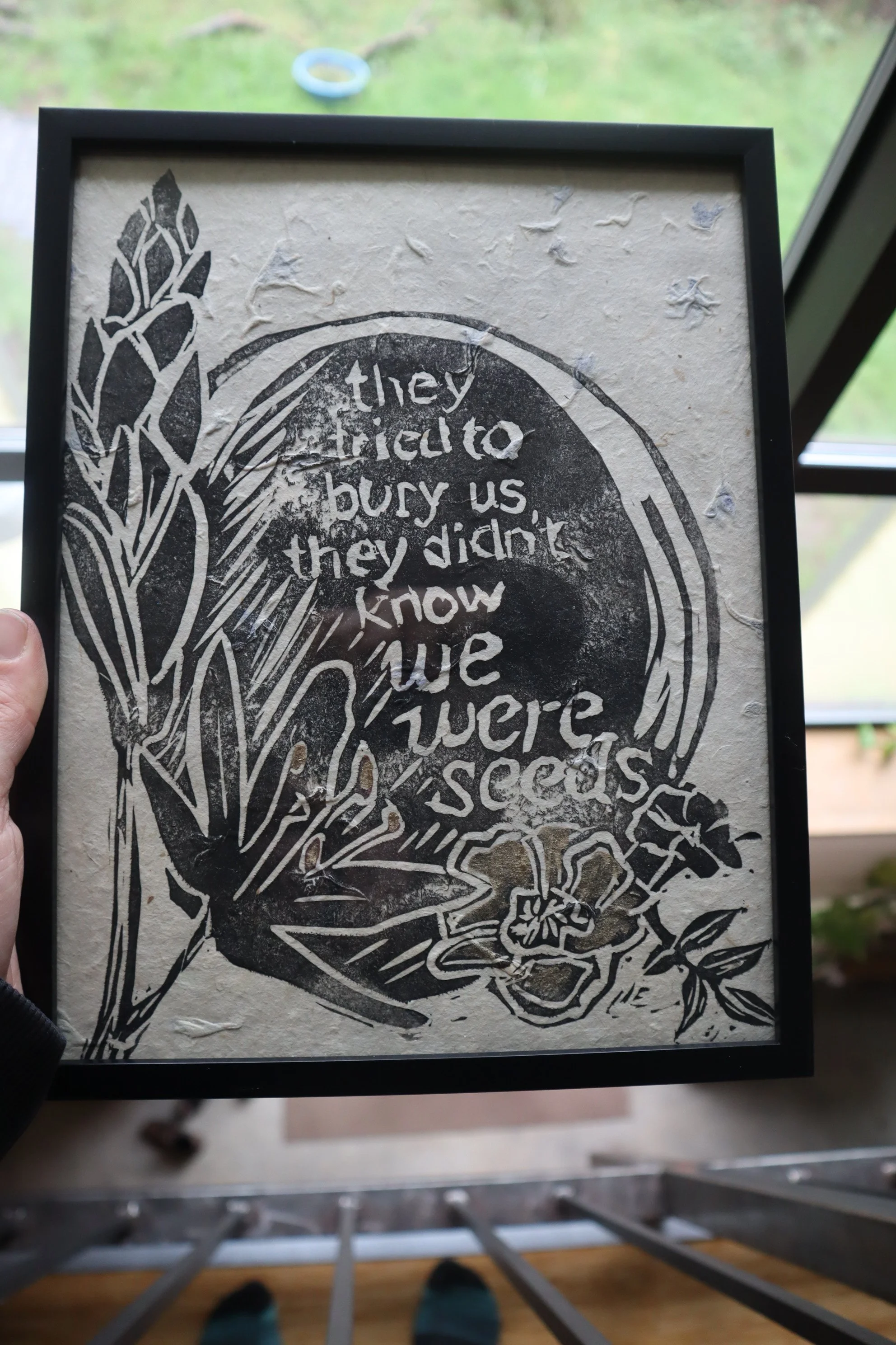 A framed black-and-white illustration with the text, "they didn't bury us, they didn't know we were seeds" alongside drawings of plants and flowers.